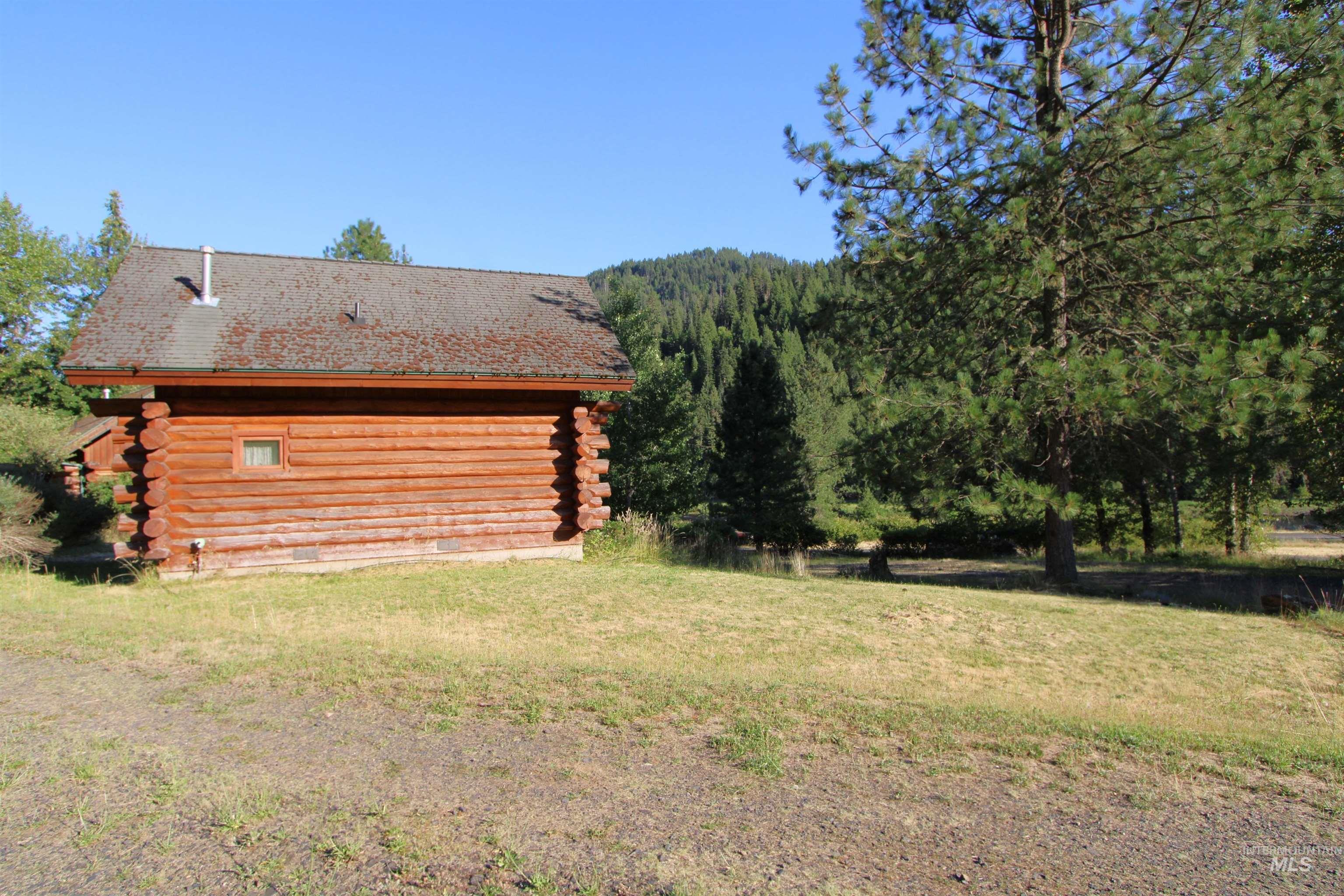 View of side of home with log exterior and a lawn
