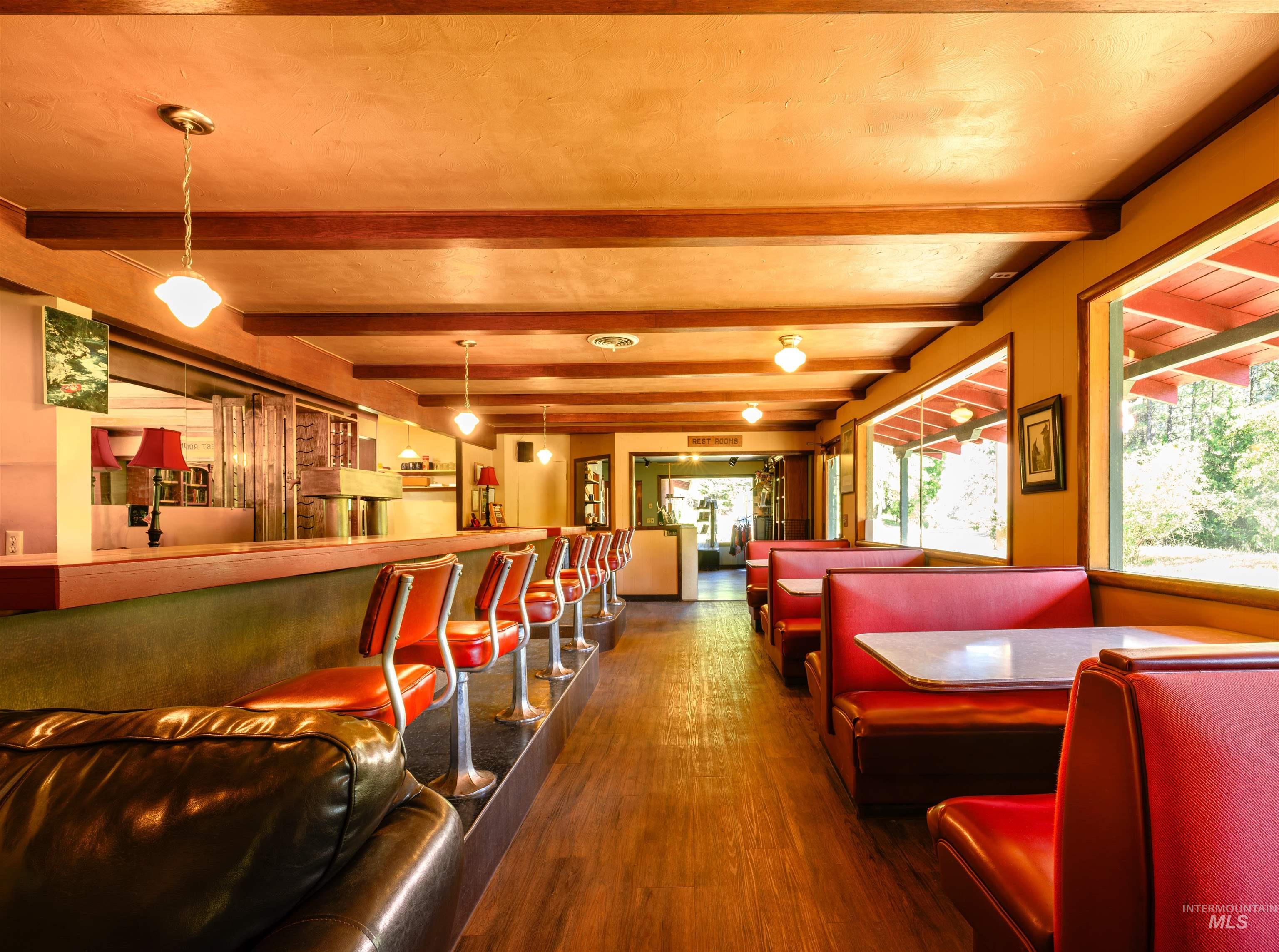 Living area featuring wood finished floors, a community bar, and beamed ceiling