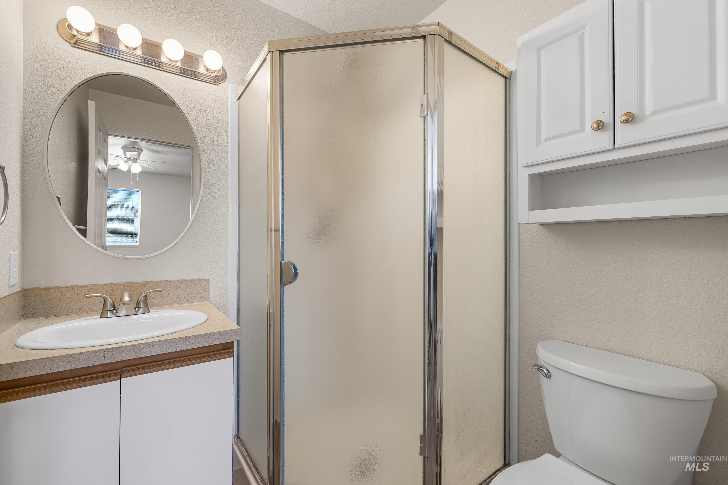 Full bathroom with a shower stall, ceiling fan, and vanity