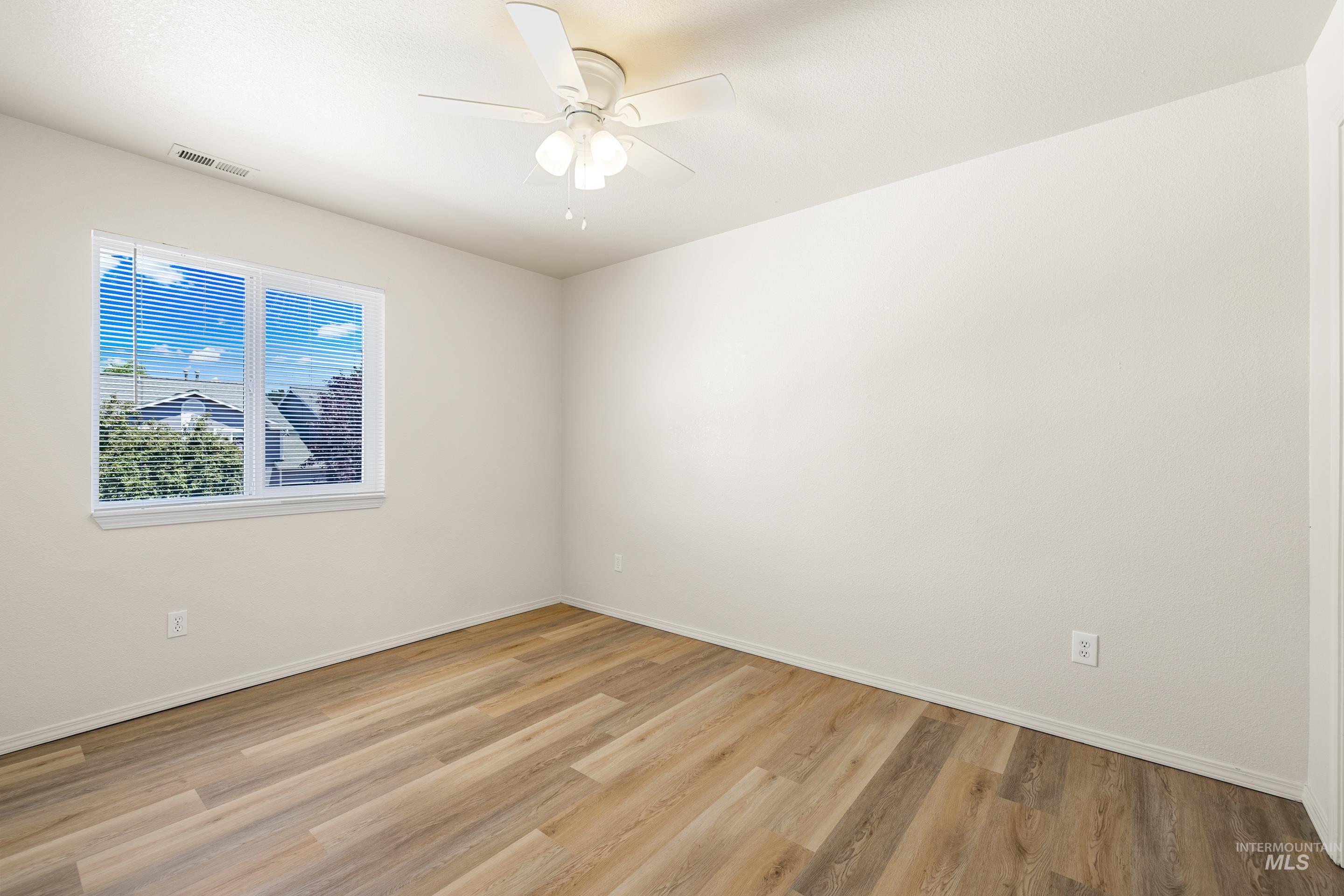 Empty room featuring light wood-style flooring and a ceiling fan