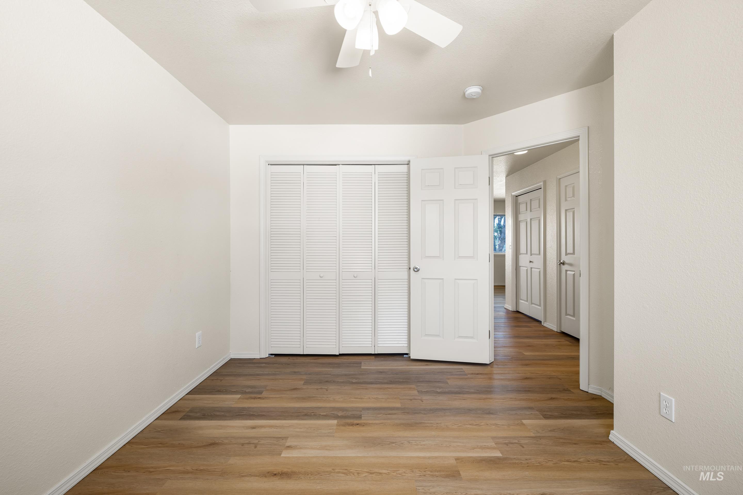 Unfurnished bedroom featuring light wood-style flooring, a closet, and a ceiling fan