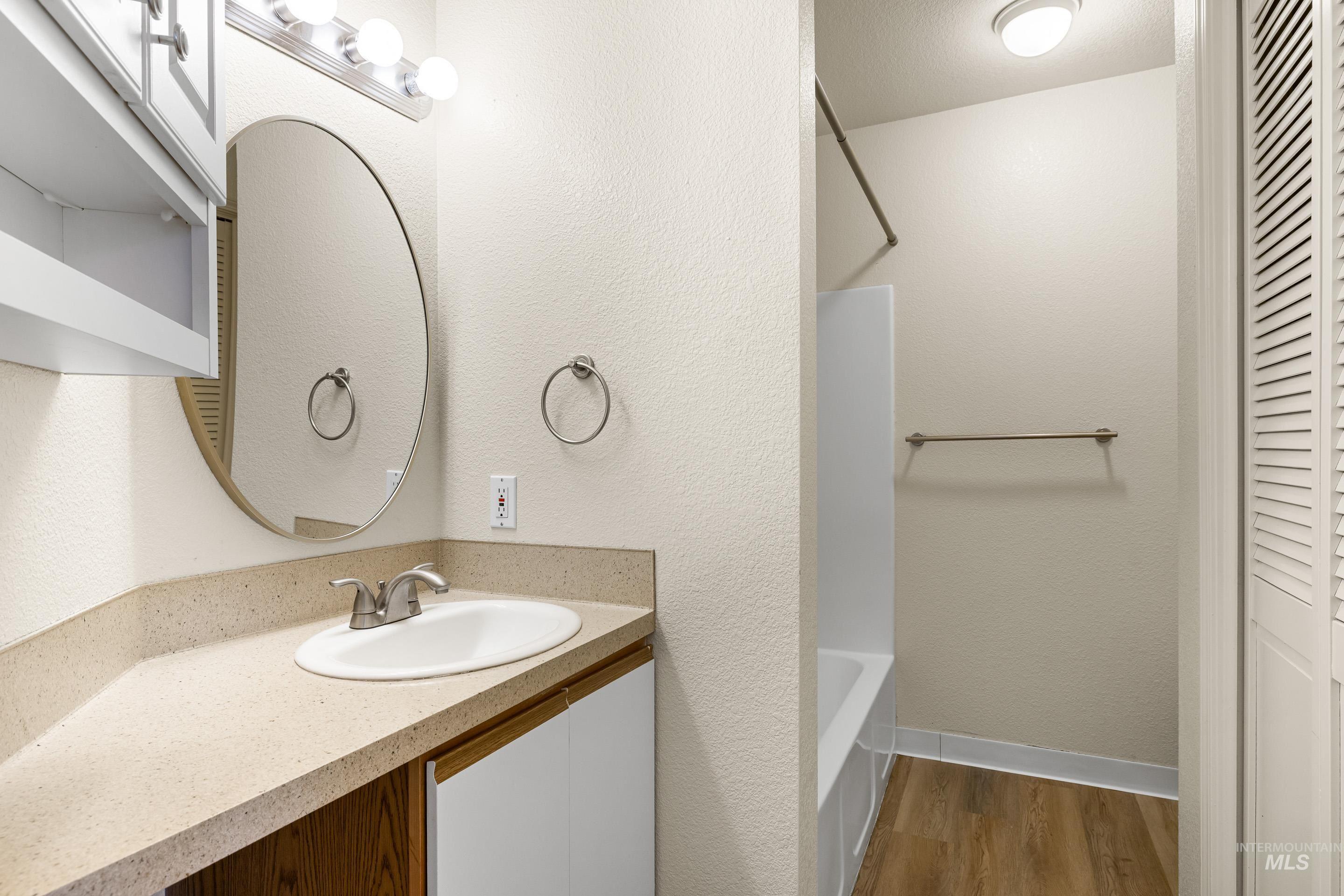 Bathroom with vanity, wood finished floors, shower / bathtub combination, and a closet