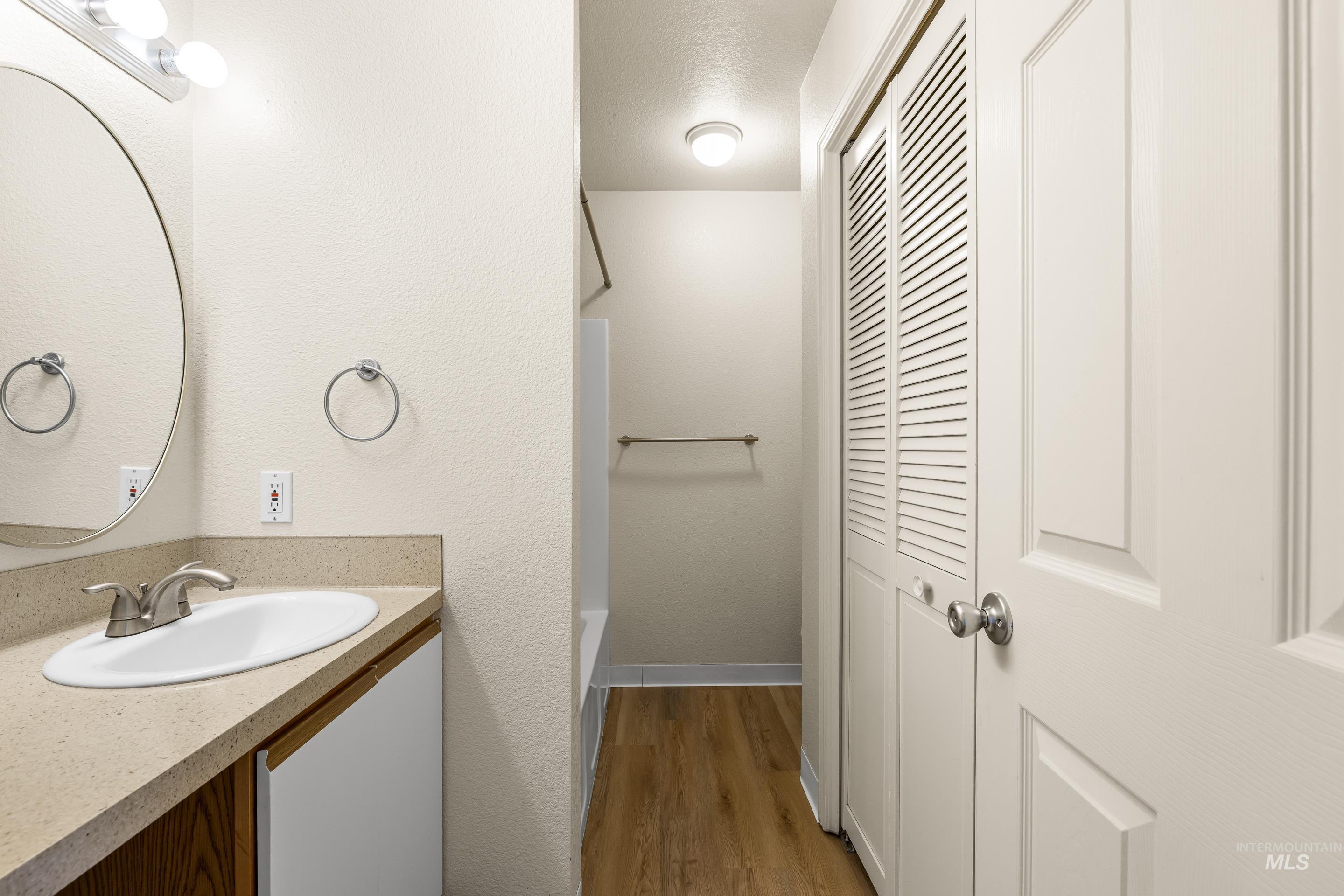 Bathroom featuring vanity, a closet, tub / shower combination, and wood finished floors