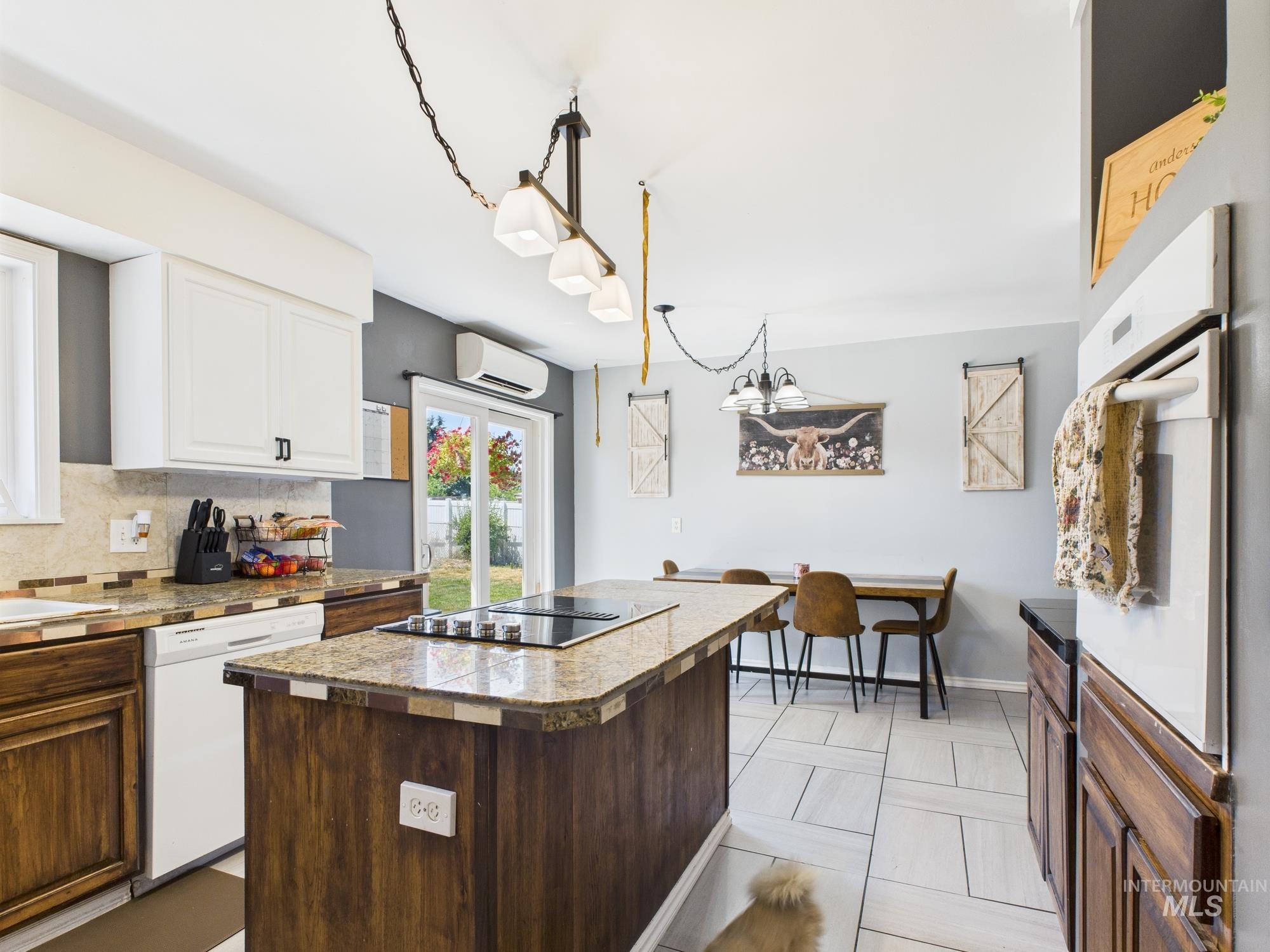 Kitchen featuring white appliances, white cabinets, decorative backsplash, a center island, and a wall mounted AC