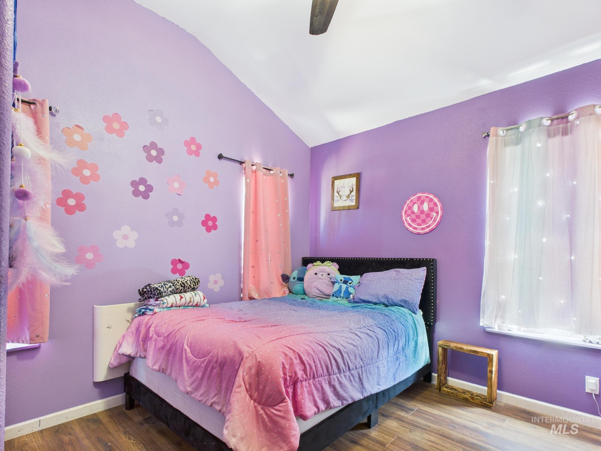 Bedroom with vaulted ceiling, wood finished floors, and a ceiling fan