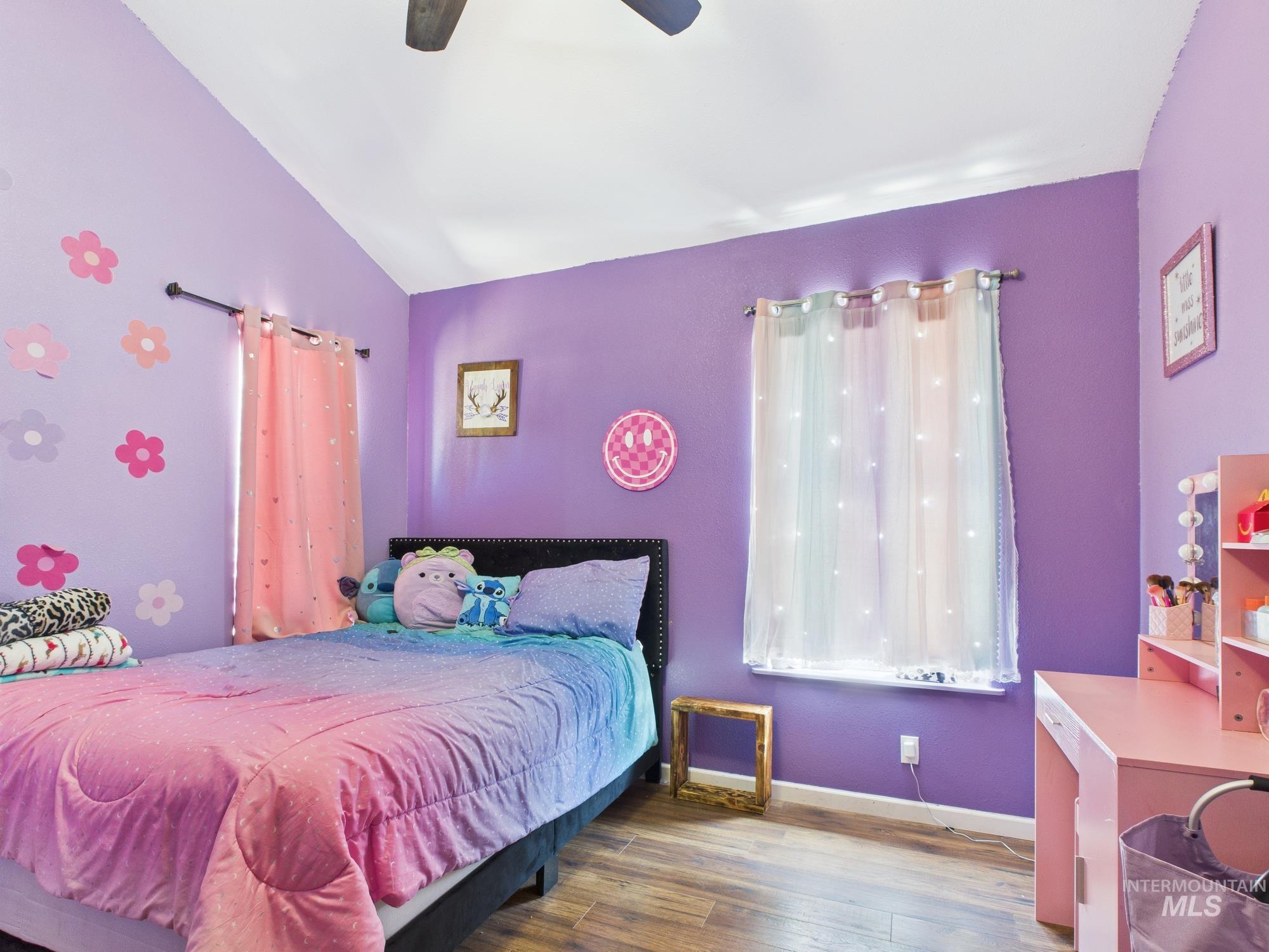 Bedroom with lofted ceiling, wood finished floors, and a ceiling fan