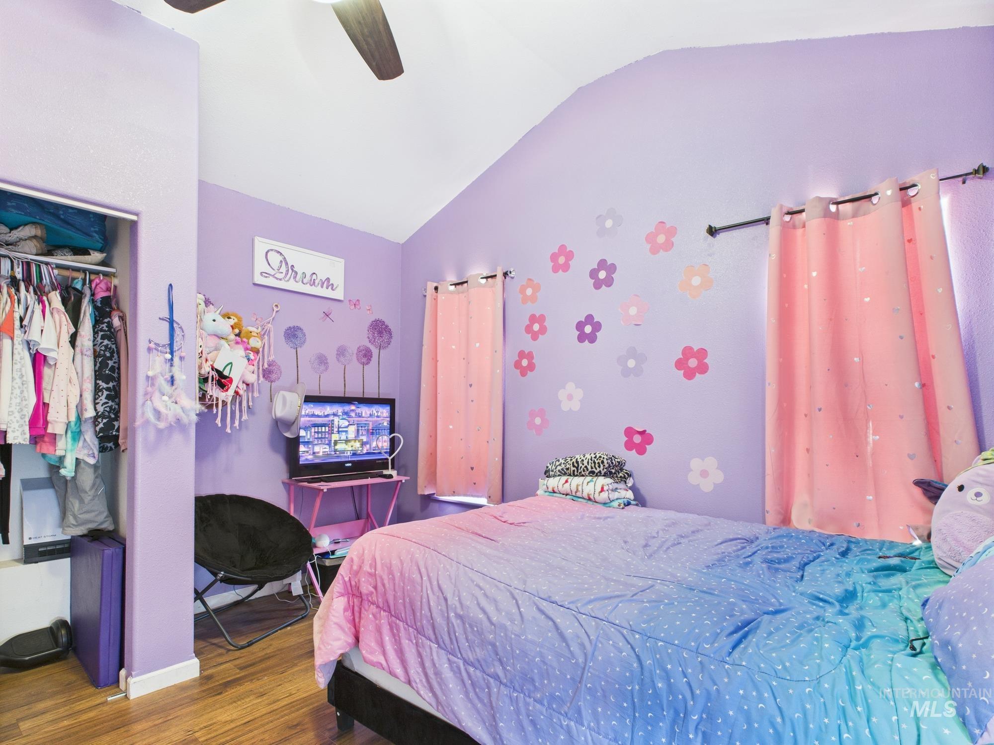 Bedroom with lofted ceiling, wood finished floors, ceiling fan, and a closet