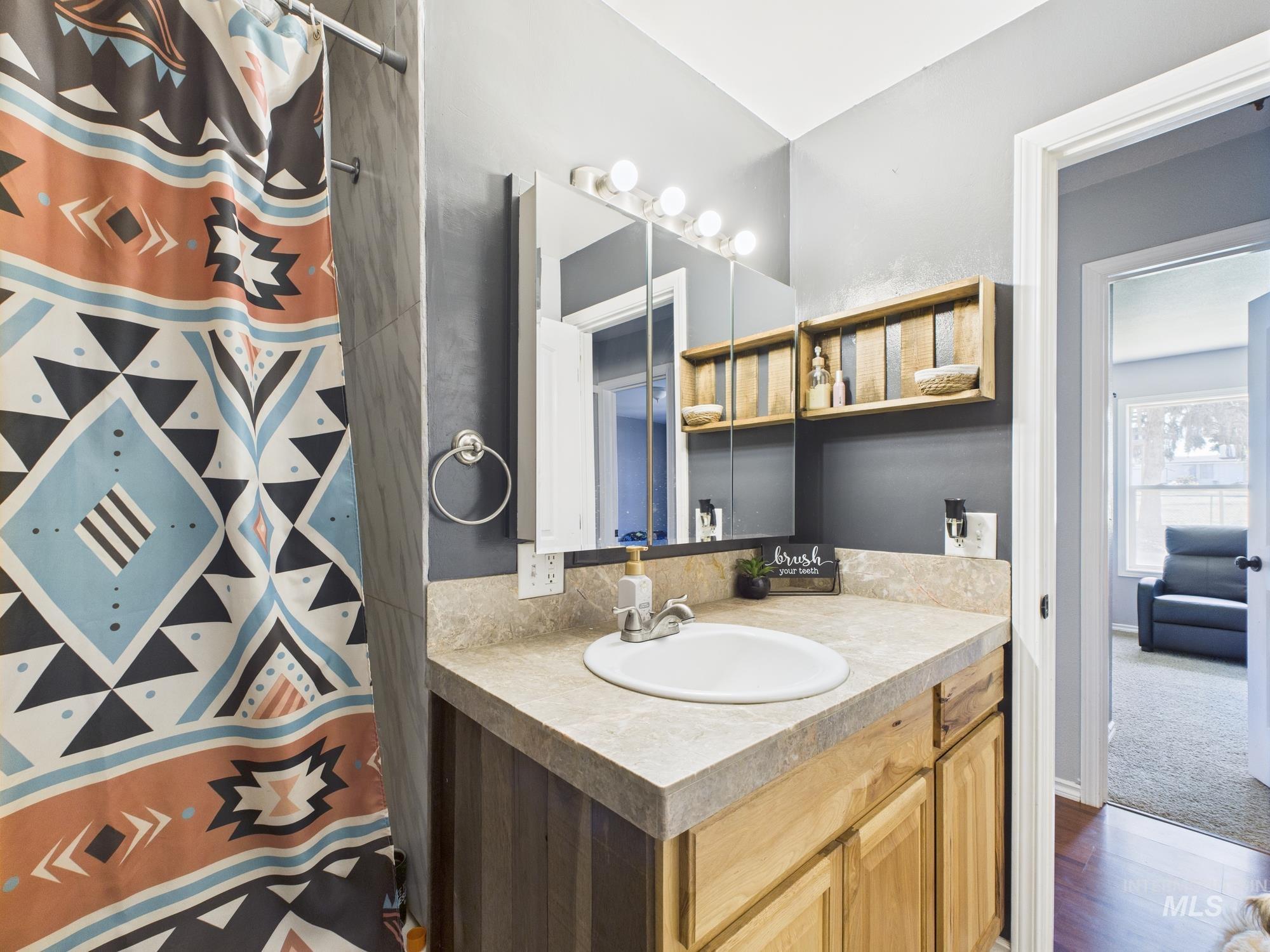 Bathroom with vanity, a shower with curtain, and wood finished floors