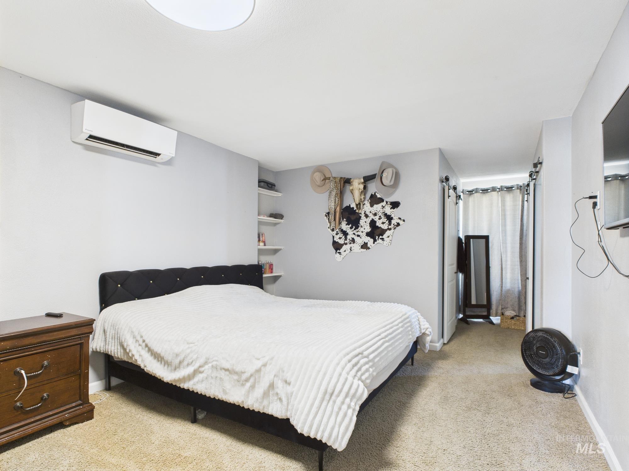Bedroom with an AC wall unit and light carpet