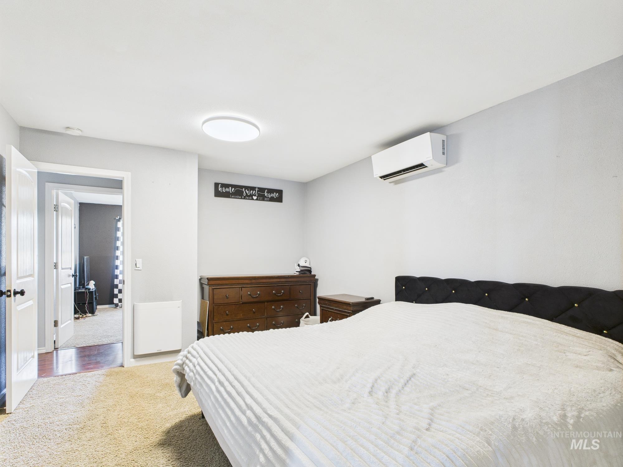 Bedroom with a wall mounted air conditioner and carpet flooring