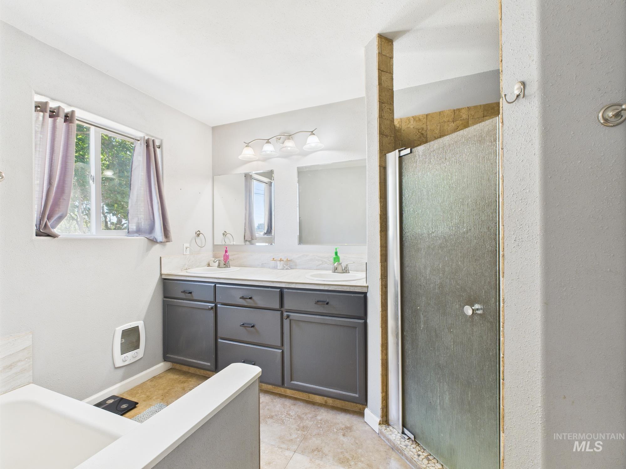 Bathroom with a shower stall, double vanity, a tub to relax in, heating unit, and tile patterned floors