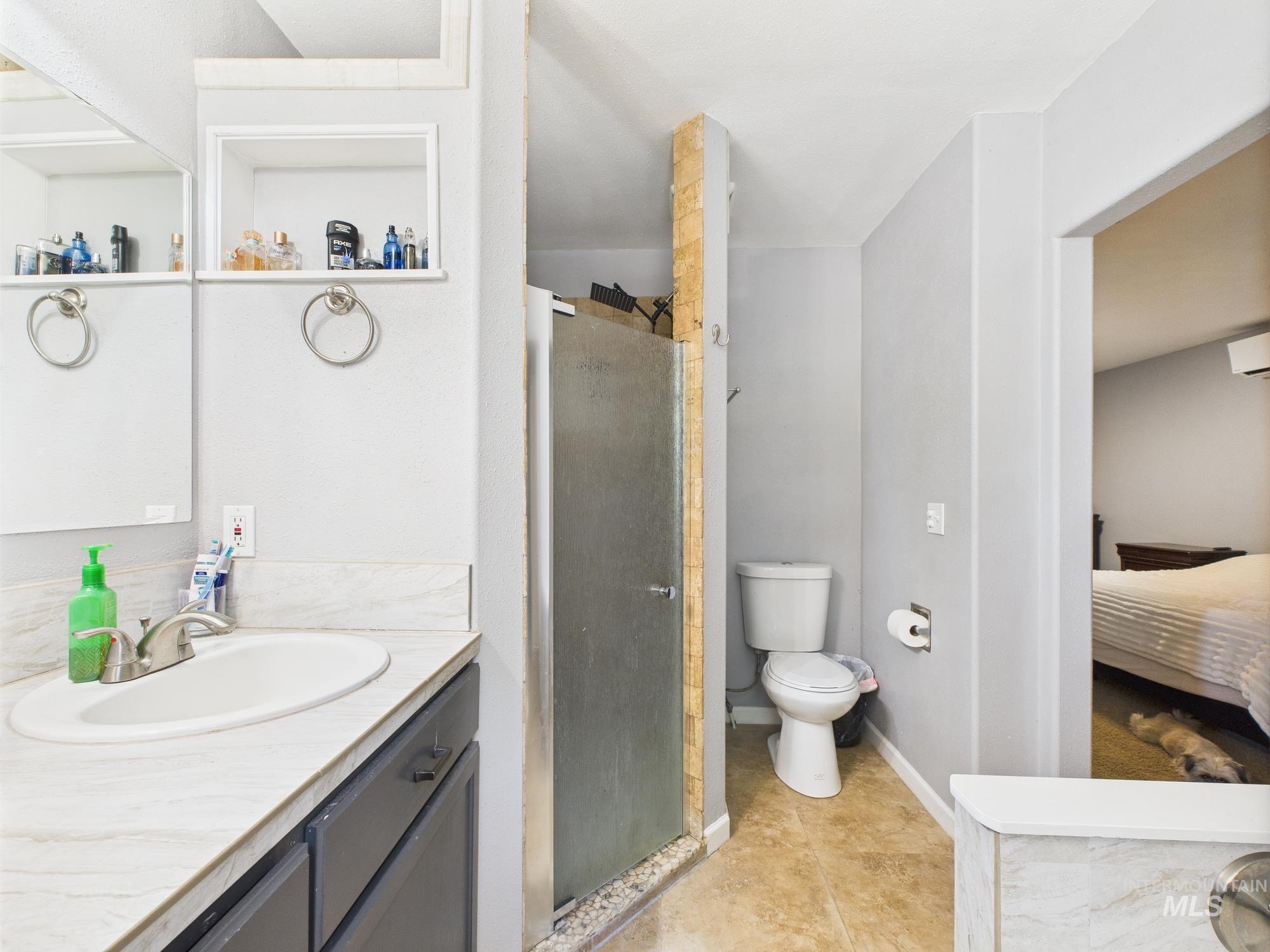 Ensuite bathroom featuring vanity, a stall shower, and a wall unit AC
