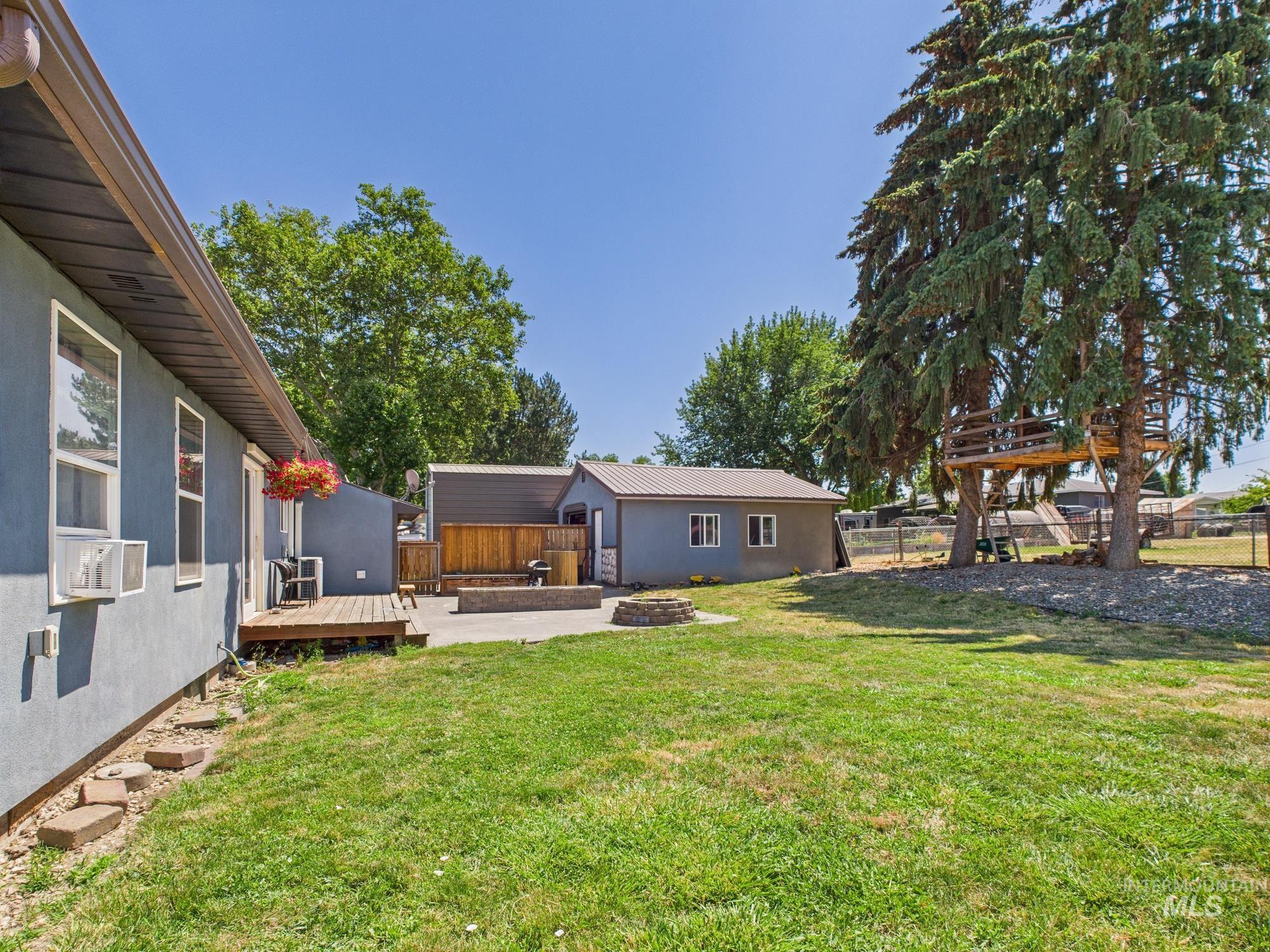 Fenced backyard featuring an outdoor fire pit, a deck, and cooling unit