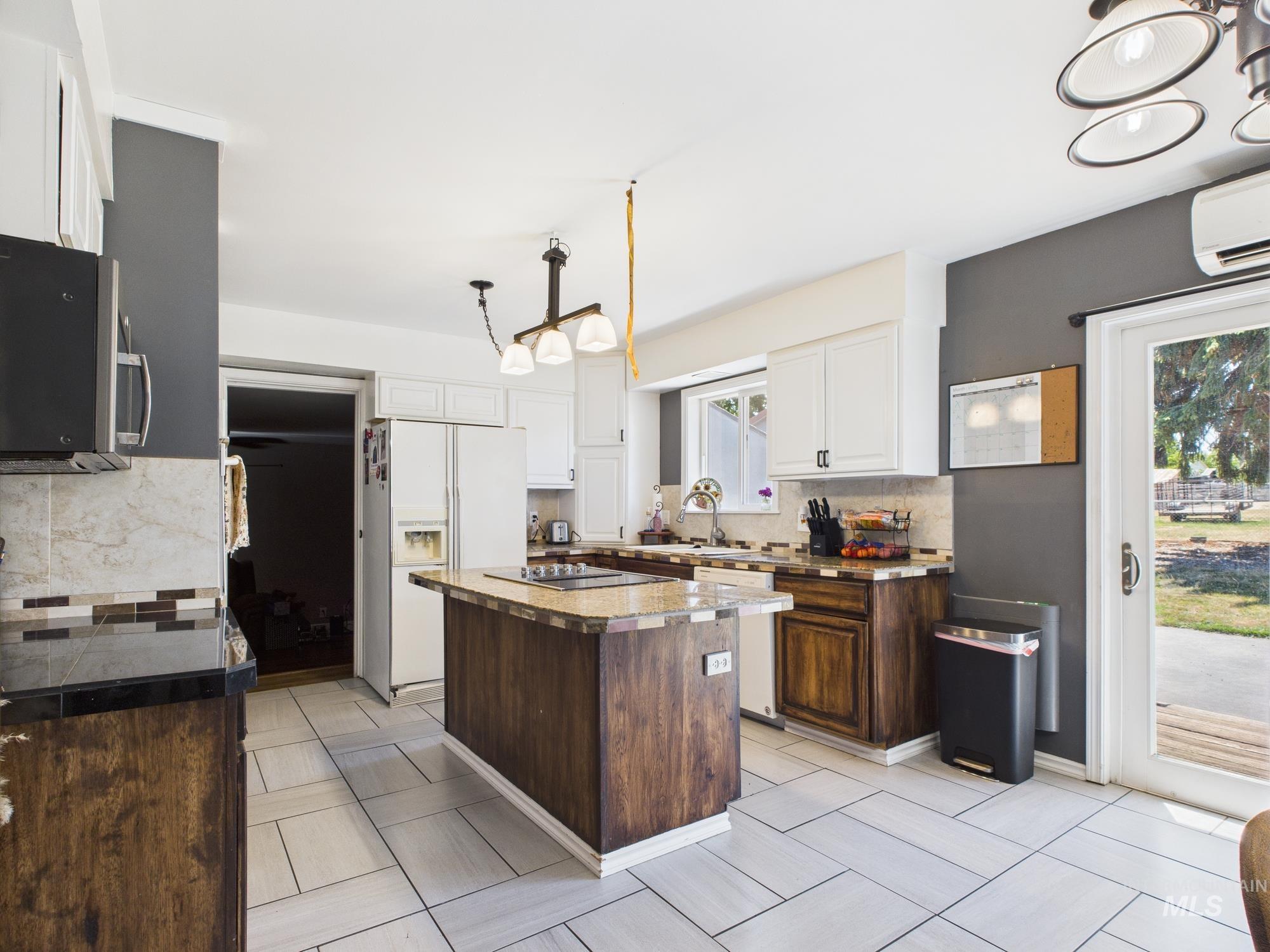 Kitchen with white appliances, a wall mounted air conditioner, tasteful backsplash, and white cabinets