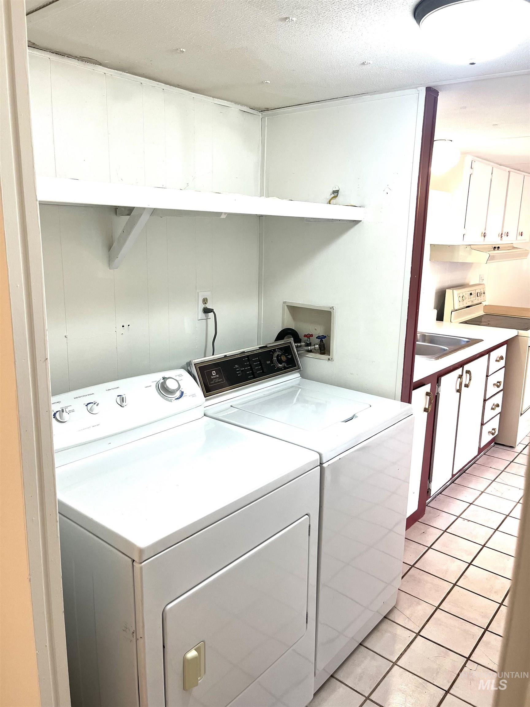 Washroom featuring separate washer and dryer, light tile patterned floors, and a textured ceiling
