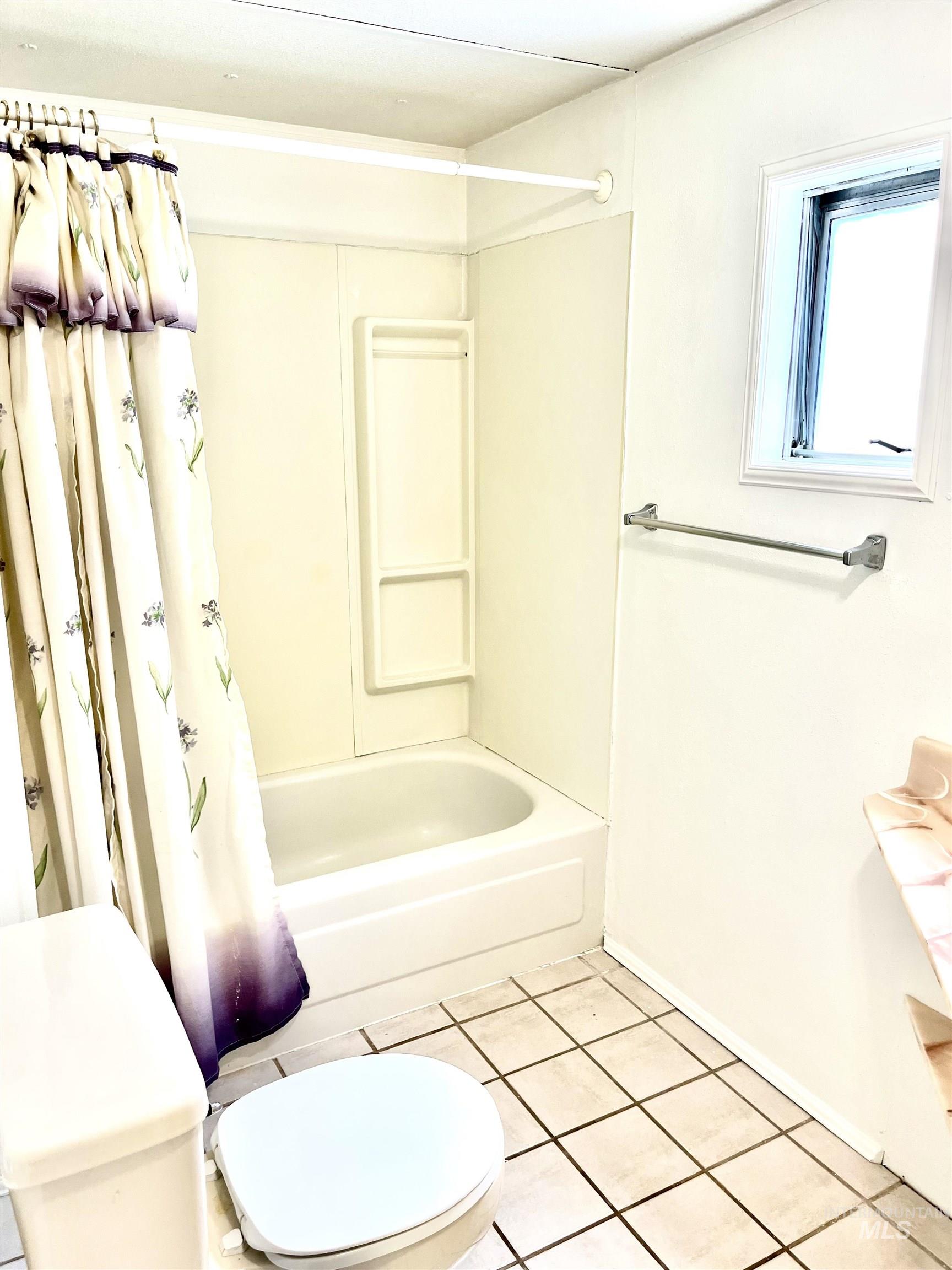 Full bath with shower / bathtub combination with curtain and tile patterned floors