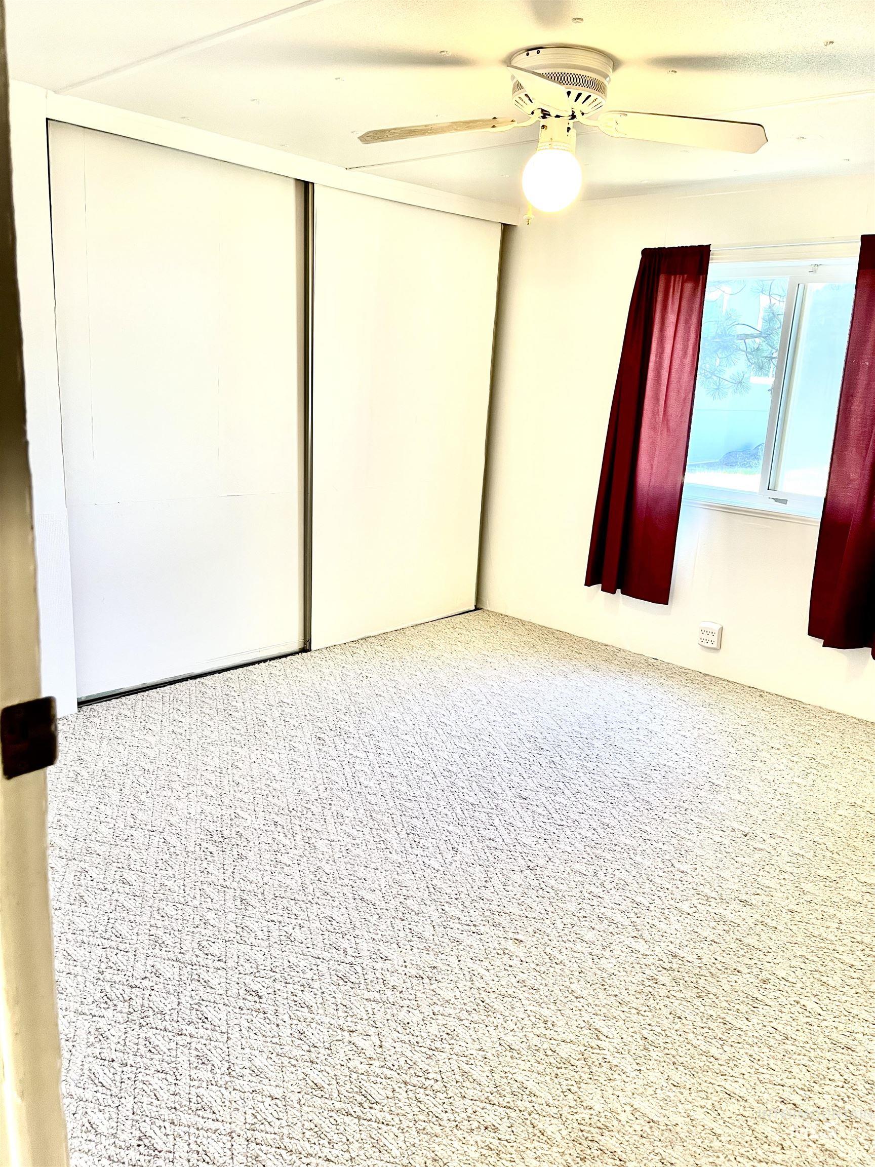 Empty room featuring carpet flooring and ceiling fan