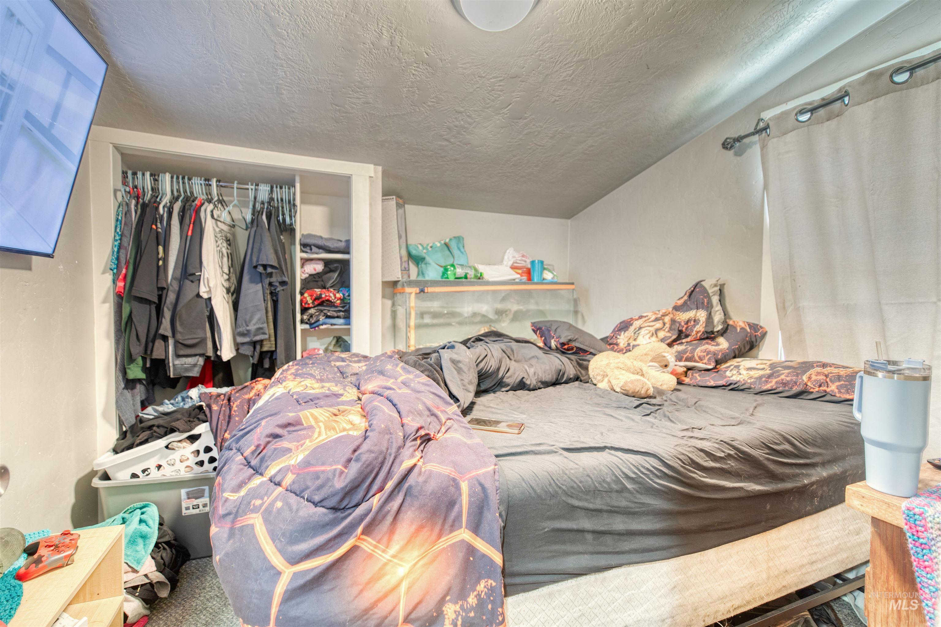 Bedroom with a textured ceiling and a closet