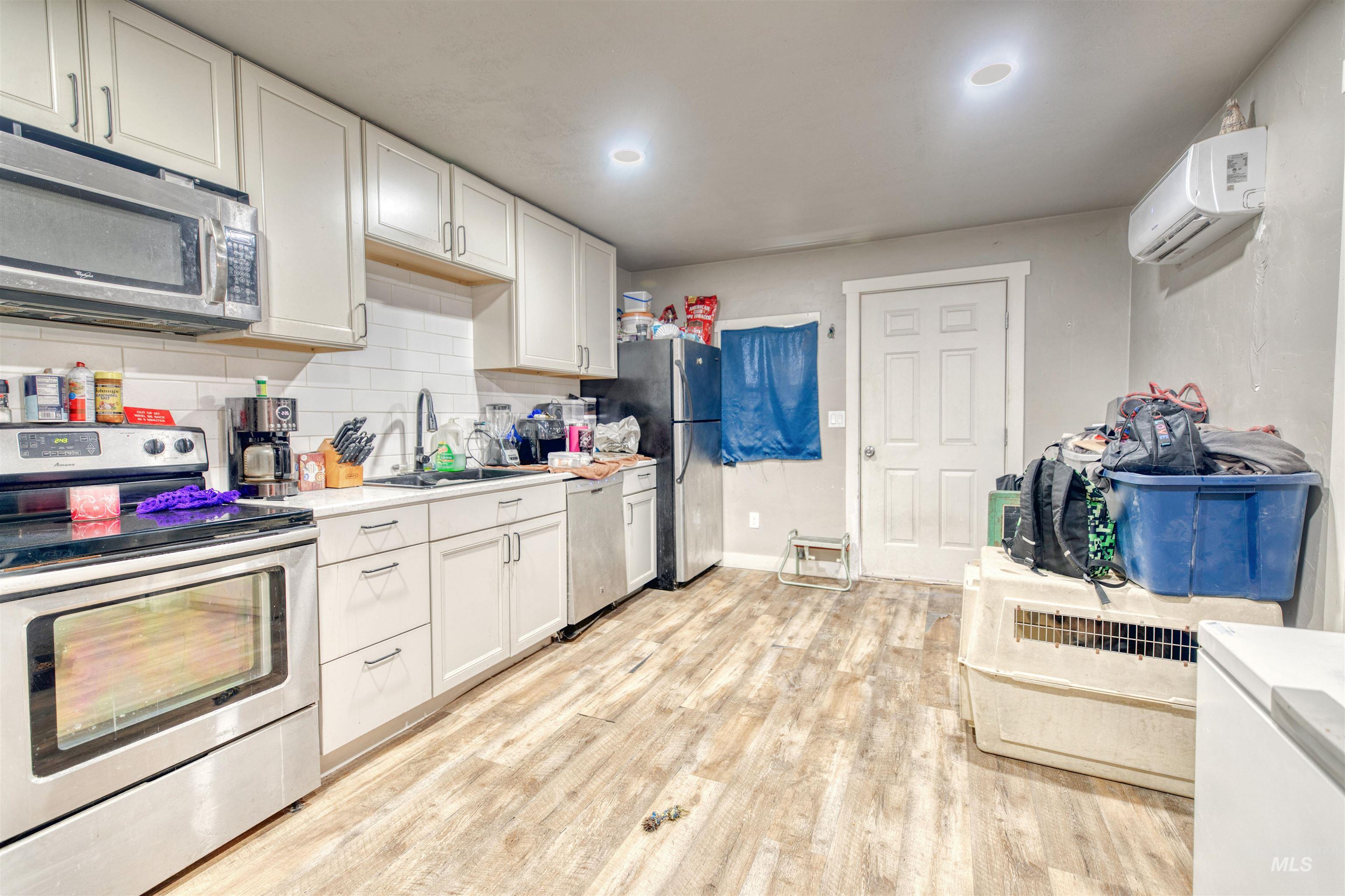 Kitchen featuring stainless steel appliances, a wall mounted air conditioner, light countertops, white cabinets, and recessed lighting