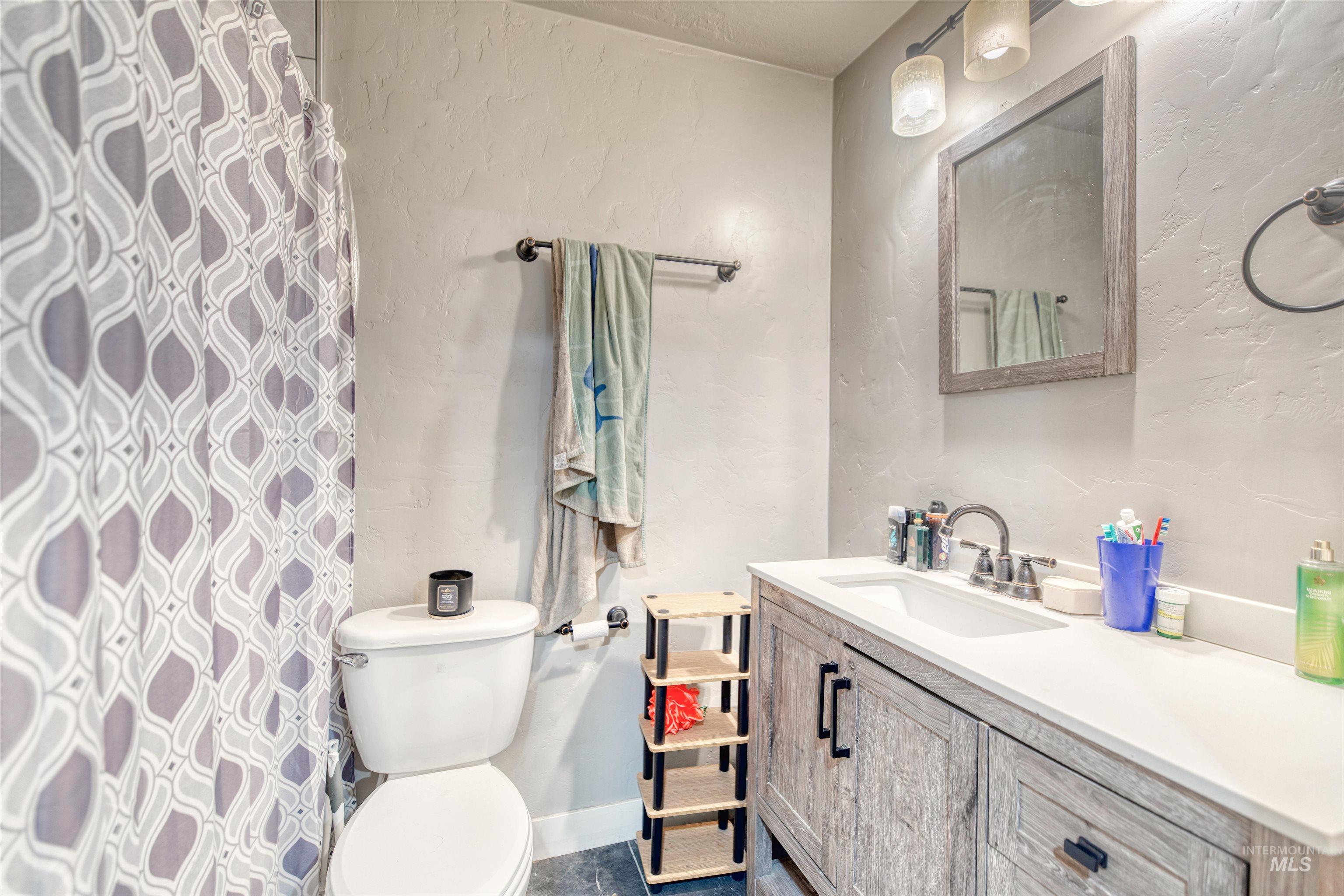Full bath featuring vanity, a textured wall, and curtained shower