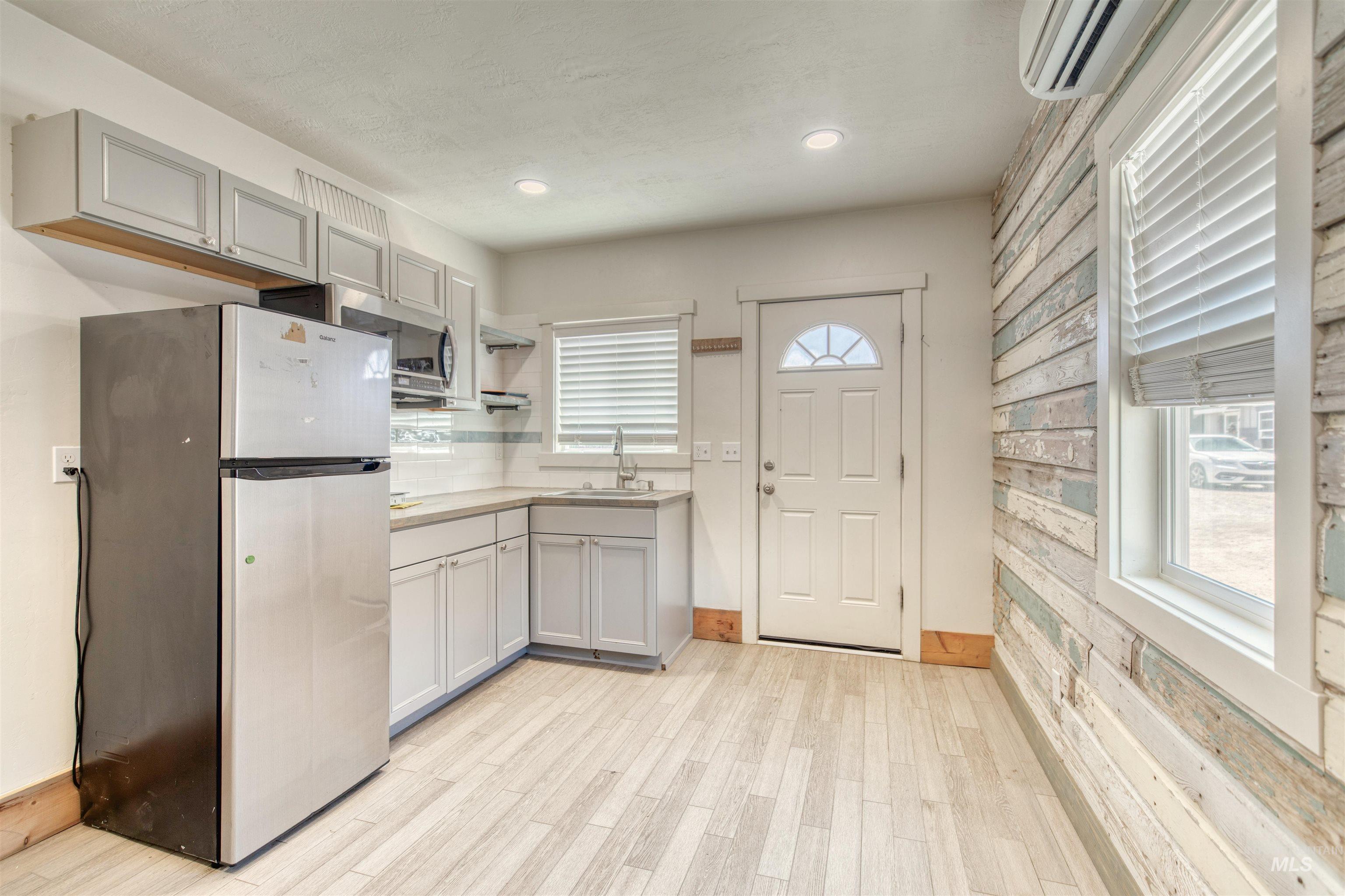 Kitchen with appliances with stainless steel finishes, healthy amount of natural light, an AC wall unit, light countertops, and recessed lighting