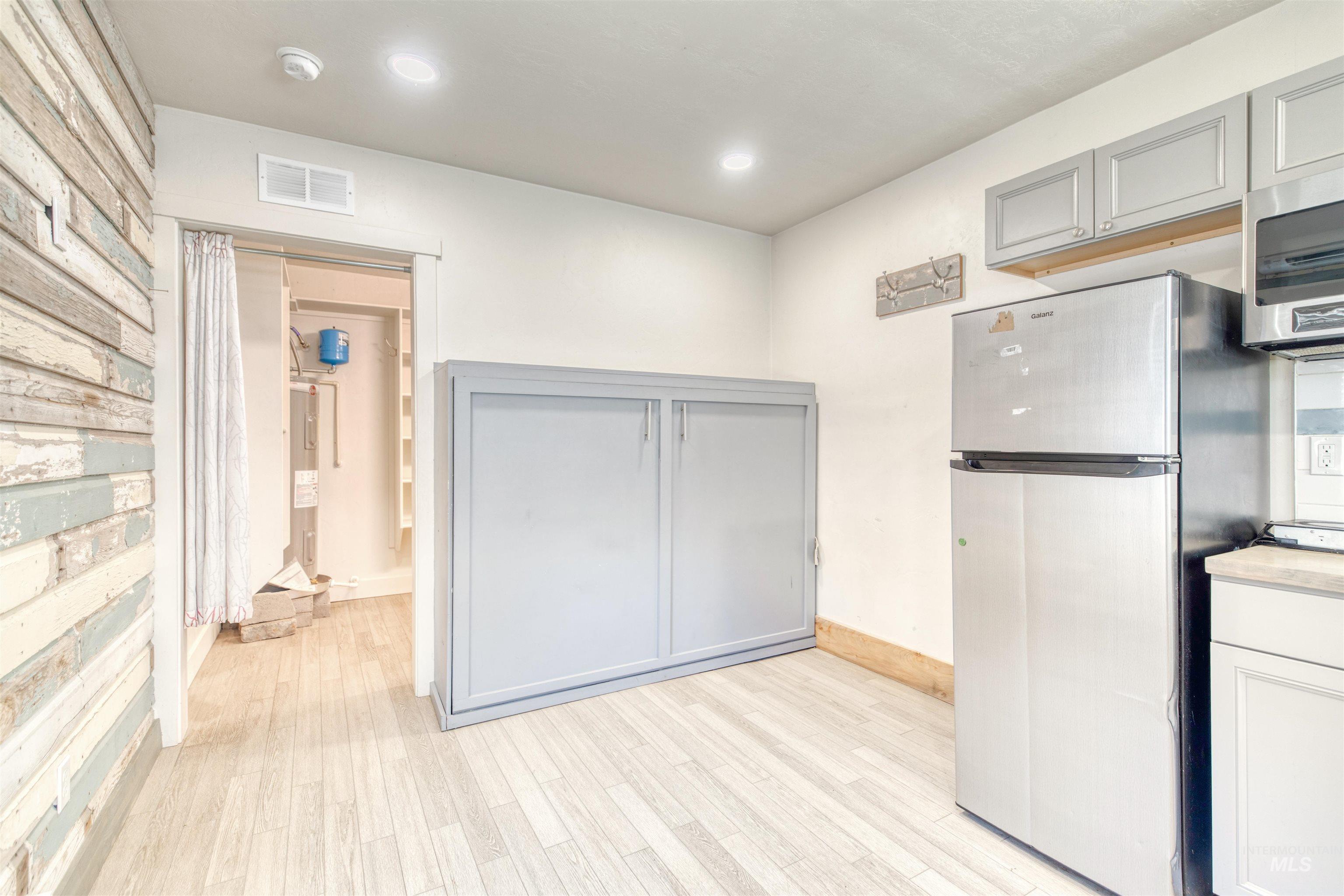 Kitchen with appliances with stainless steel finishes, gray cabinetry, light wood-style floors, light countertops, and recessed lighting
