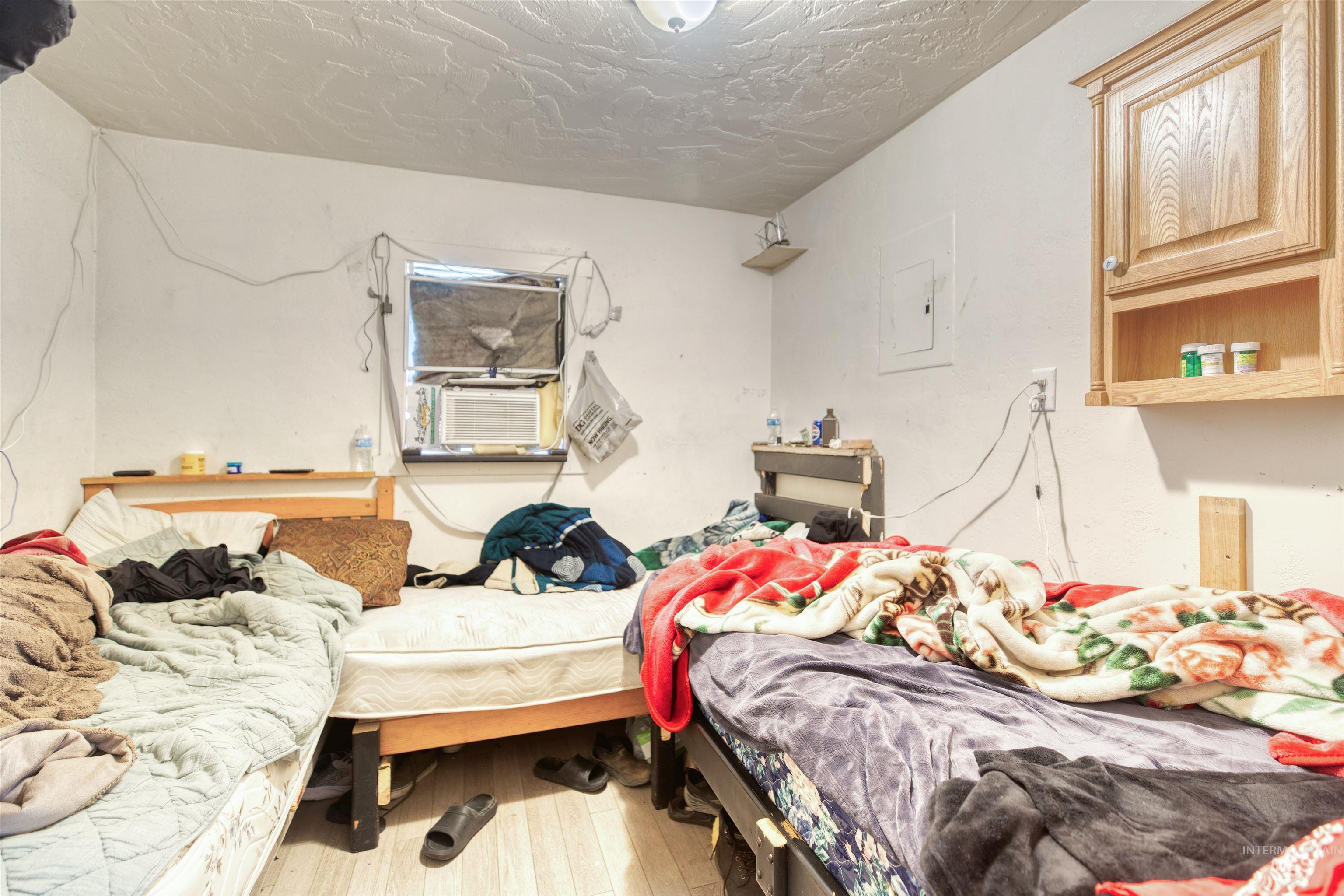 Bedroom featuring hardwood / wood-style flooring, electric panel, and cooling unit