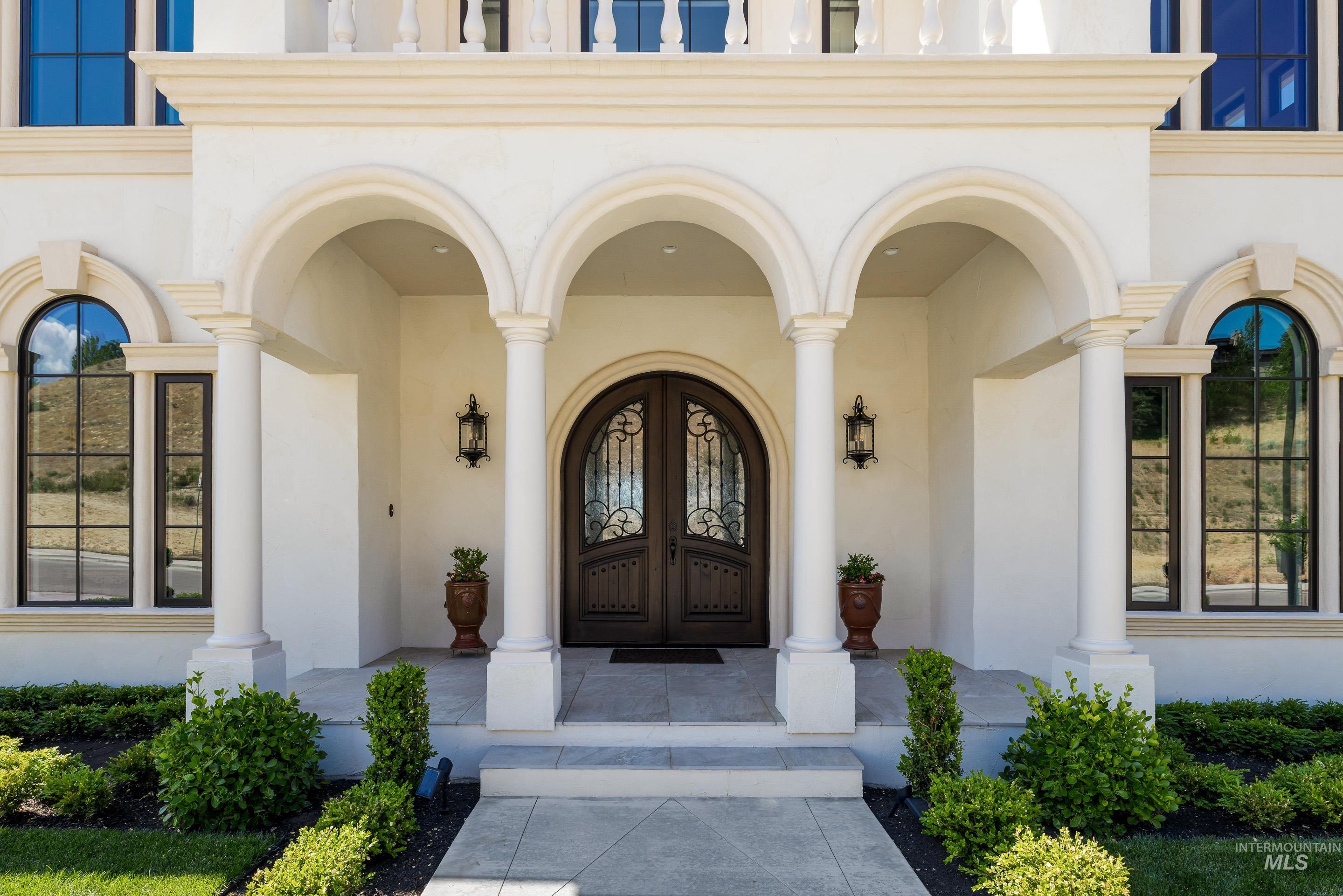 Entrance to property featuring stucco siding, covered porch, and french doors