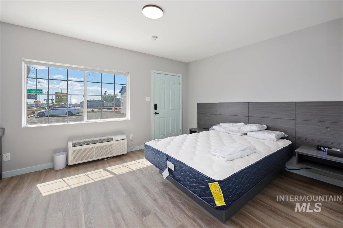 Bedroom with wood finished floors and a wall mounted AC