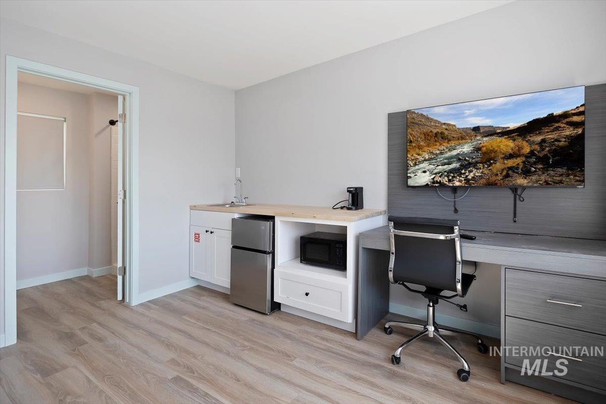 Home office with light wood finished floors and a sink