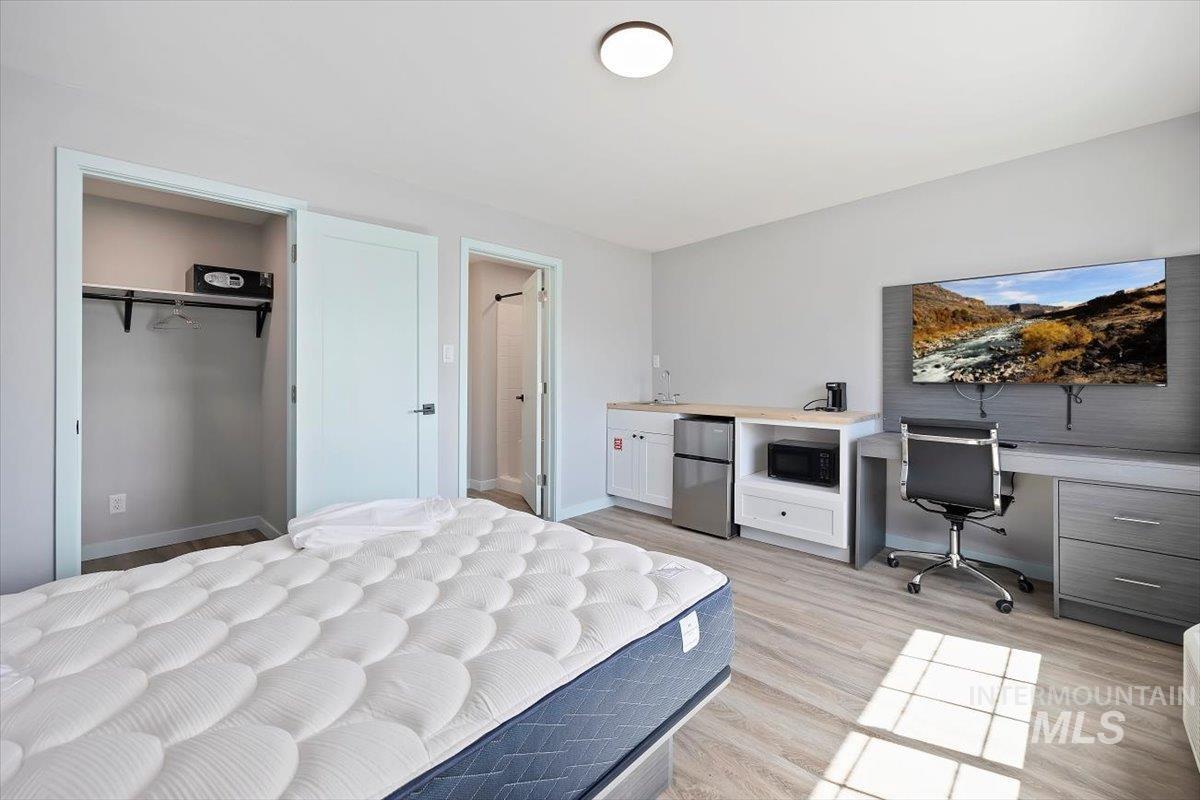 Bedroom with freestanding refrigerator, a desk, and light wood finished floors