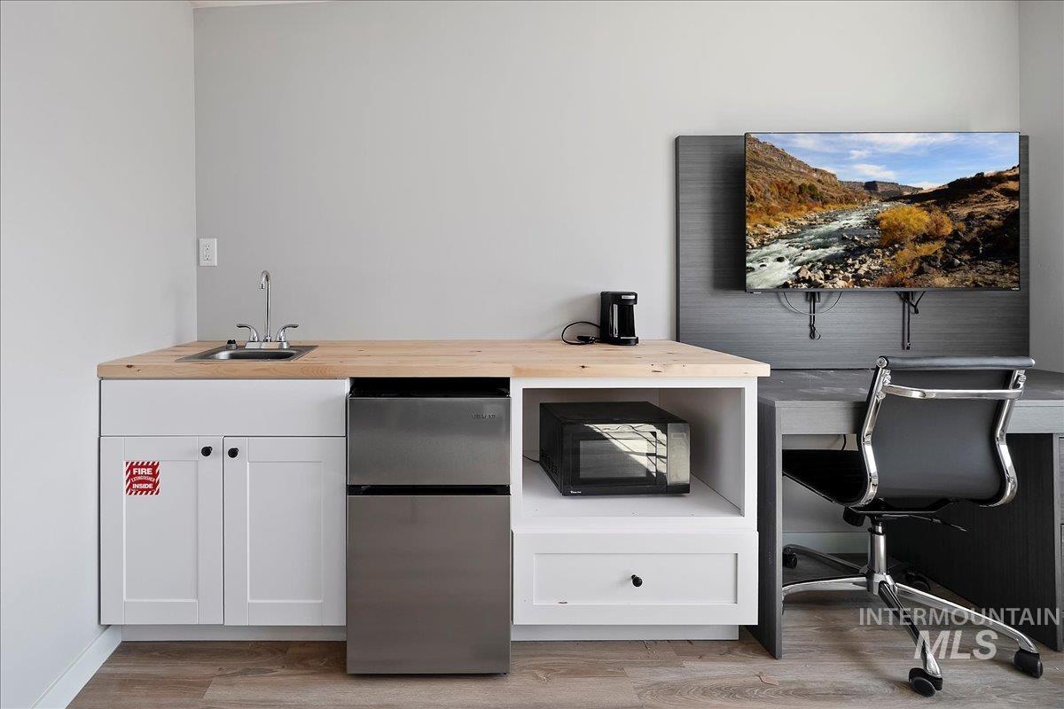 Office area featuring light wood finished floors and wet bar