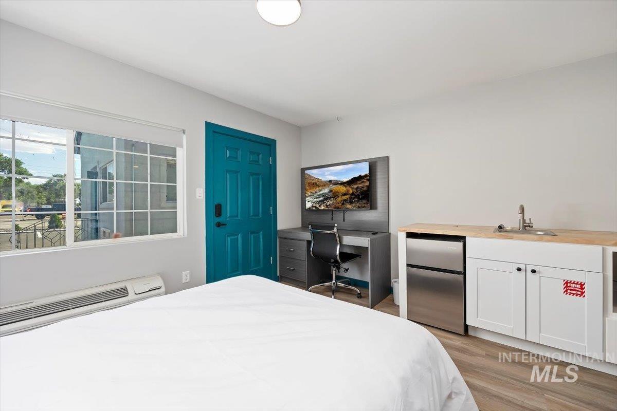 Bedroom featuring freestanding refrigerator and light wood finished floors