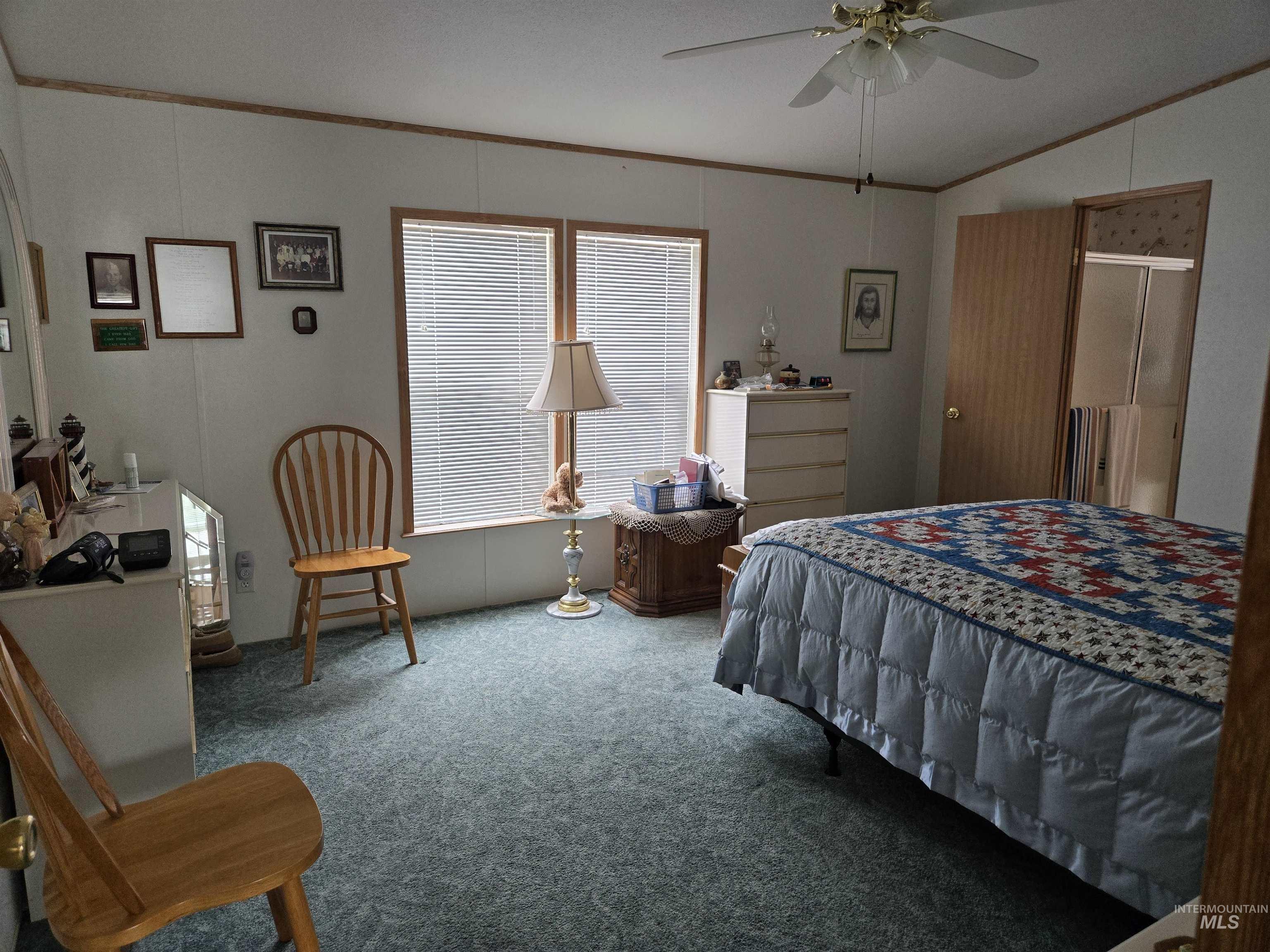 Carpeted bedroom featuring ornamental molding, lofted ceiling, and ceiling fan