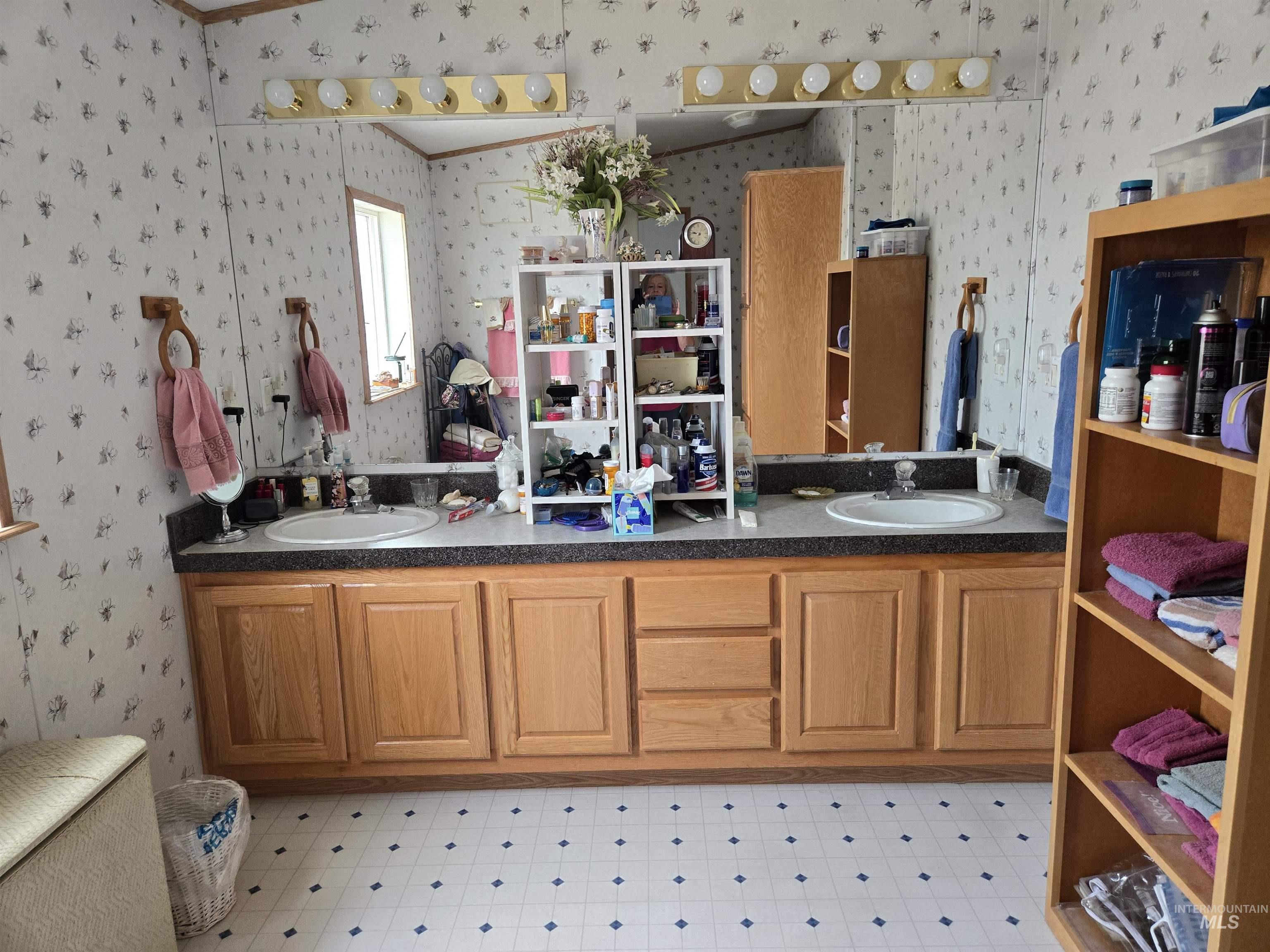 Bathroom featuring wallpapered walls, double vanity, crown molding, and tile patterned floors