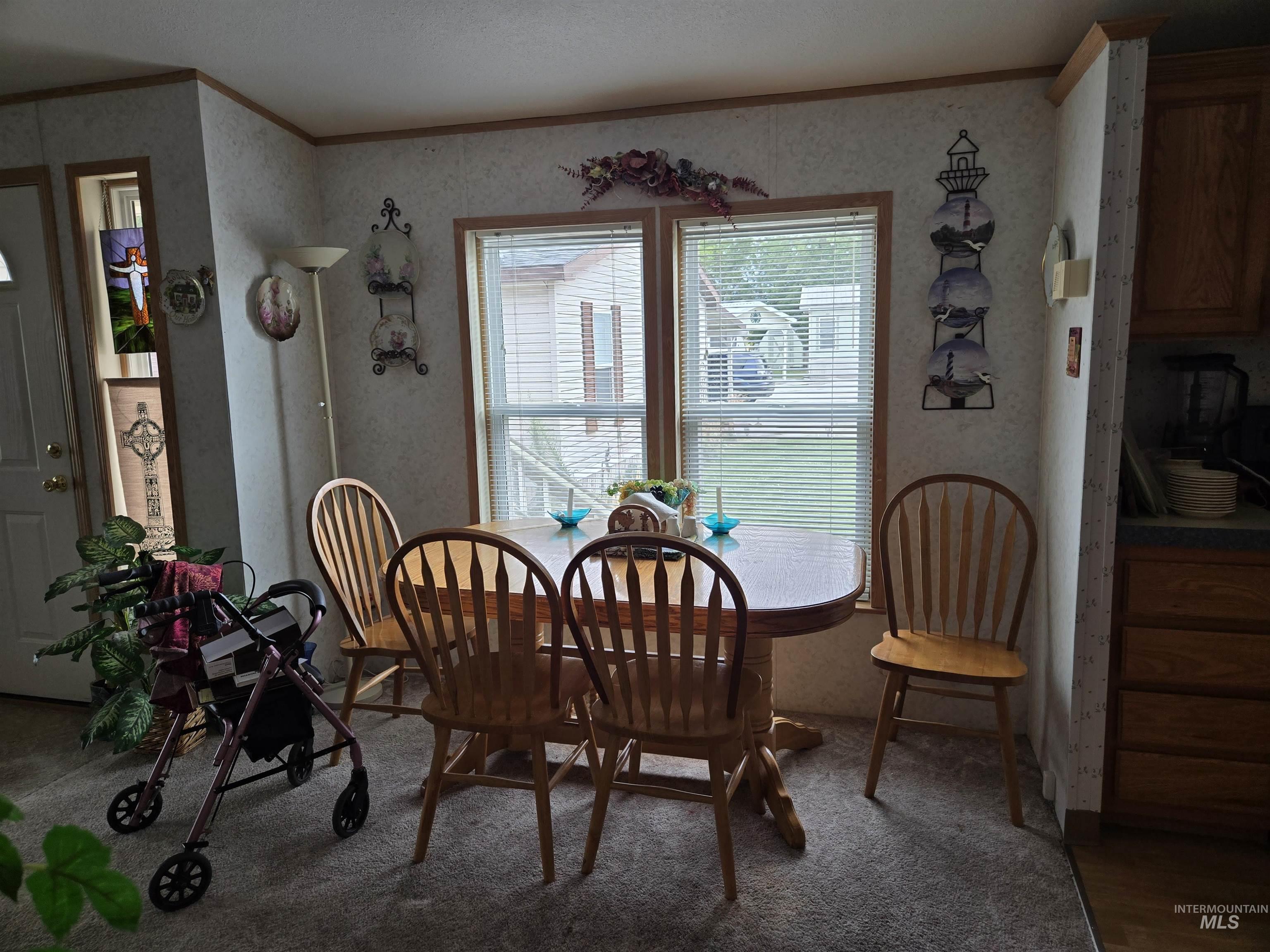 Dining room with crown molding, wallpapered walls, and carpet flooring
