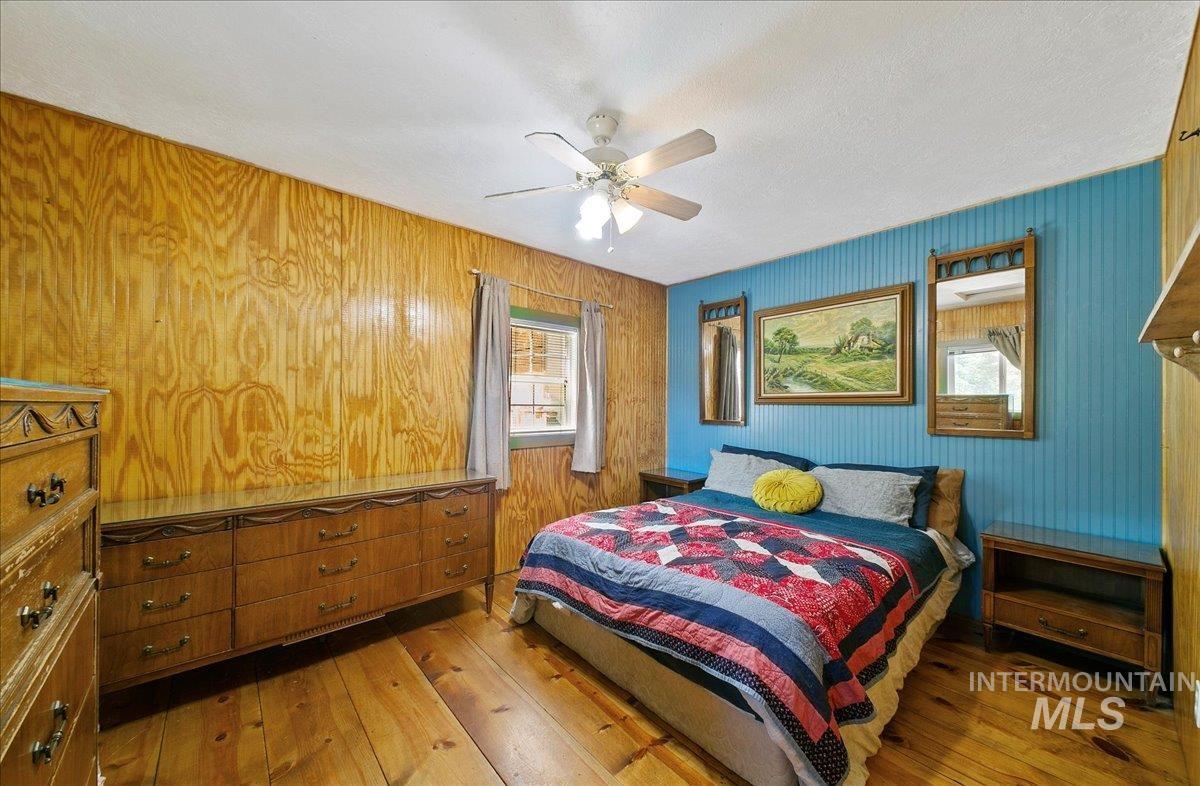 Bedroom featuring hardwood / wood-style floors, ceiling fan, and wood walls