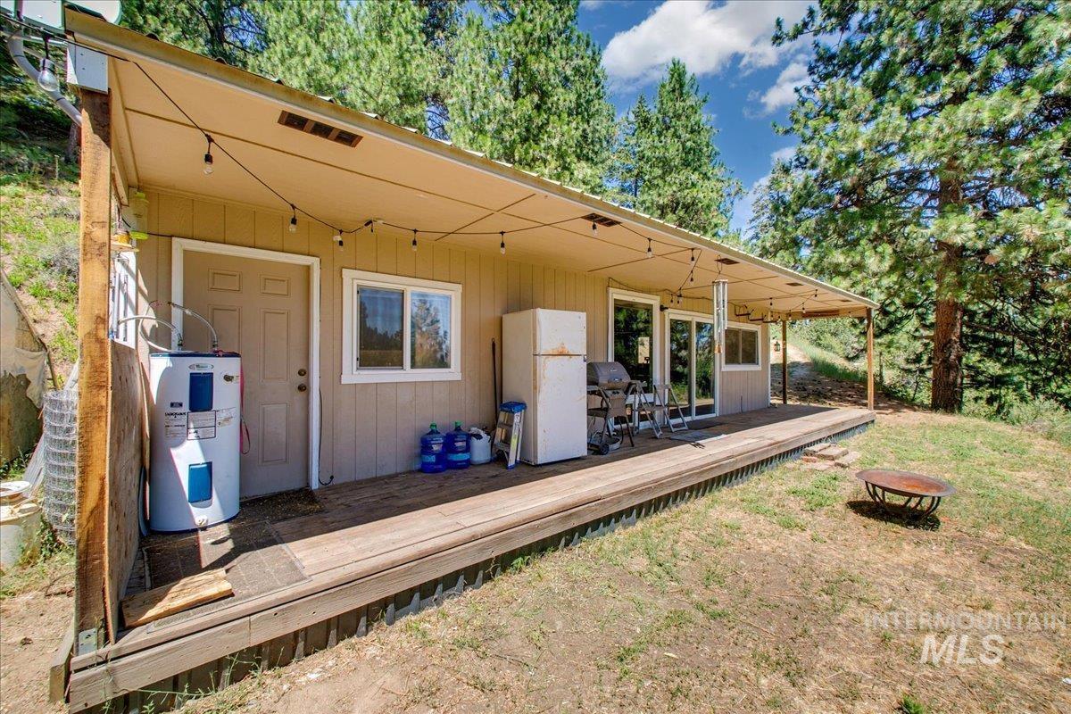 Wooden terrace featuring electric water heater, a fire pit, and a yard