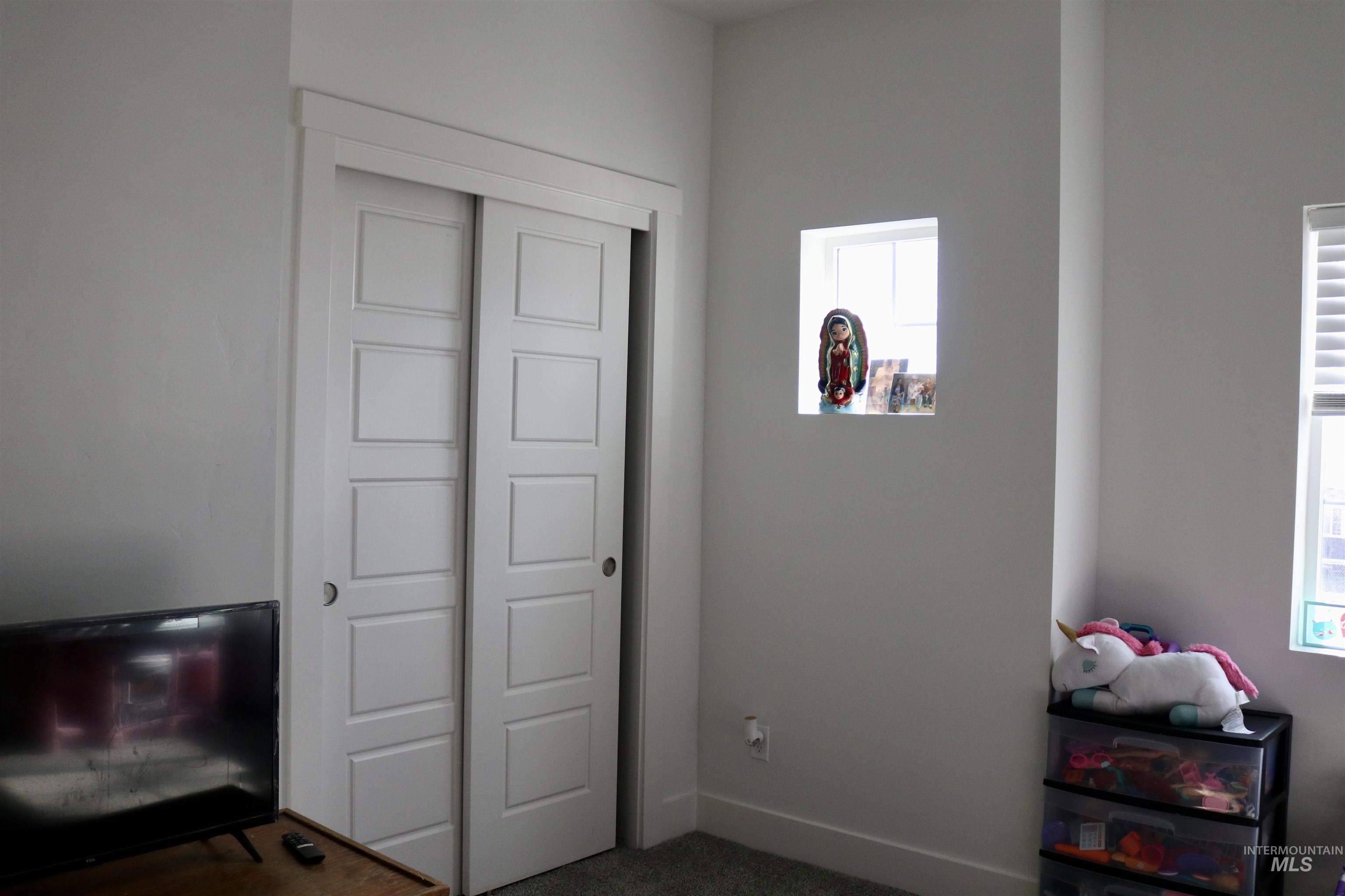 Bedroom with multiple windows, a closet, and dark colored carpet
