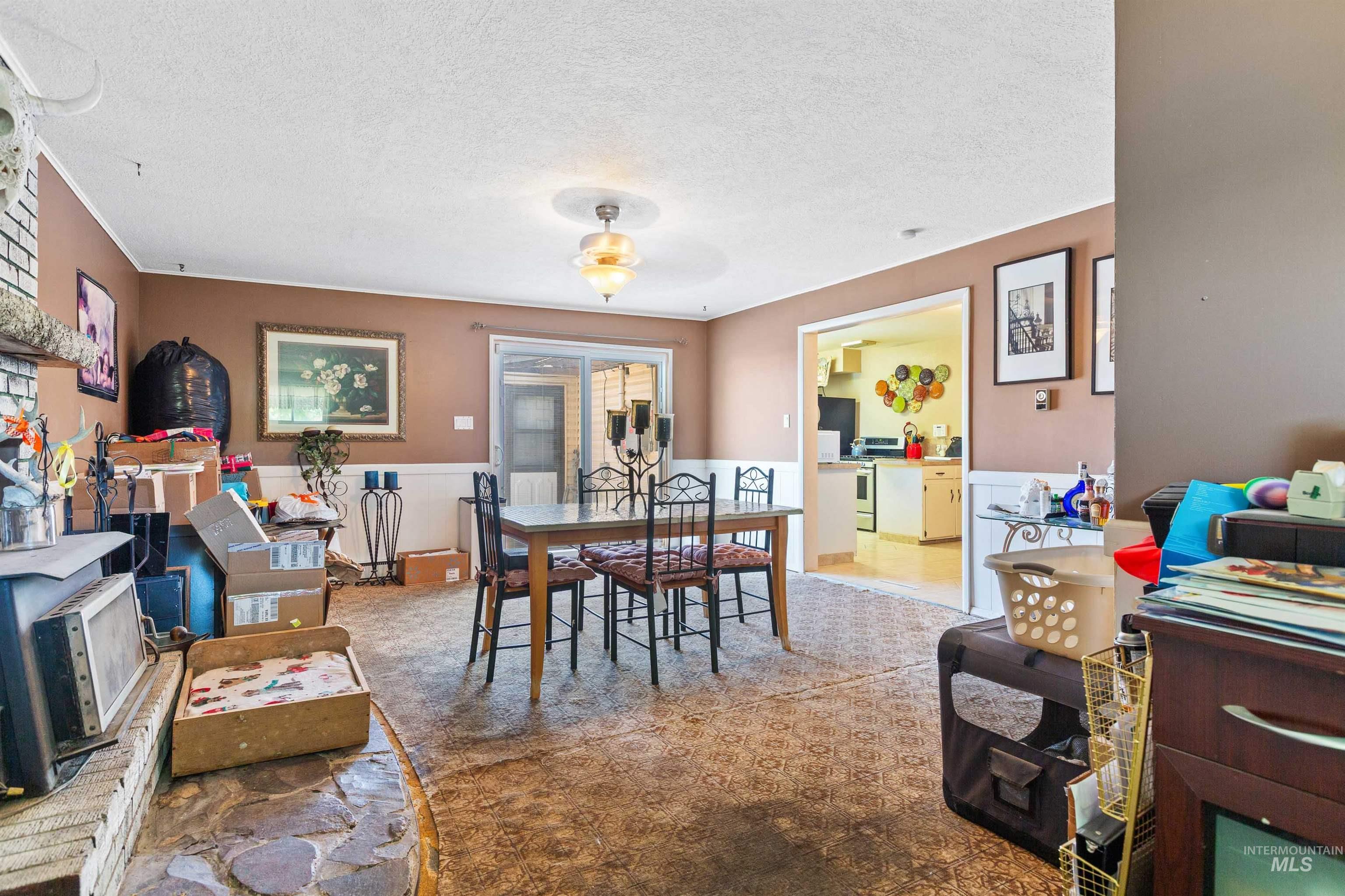 Carpeted dining area featuring a textured ceiling and a wainscoted wall