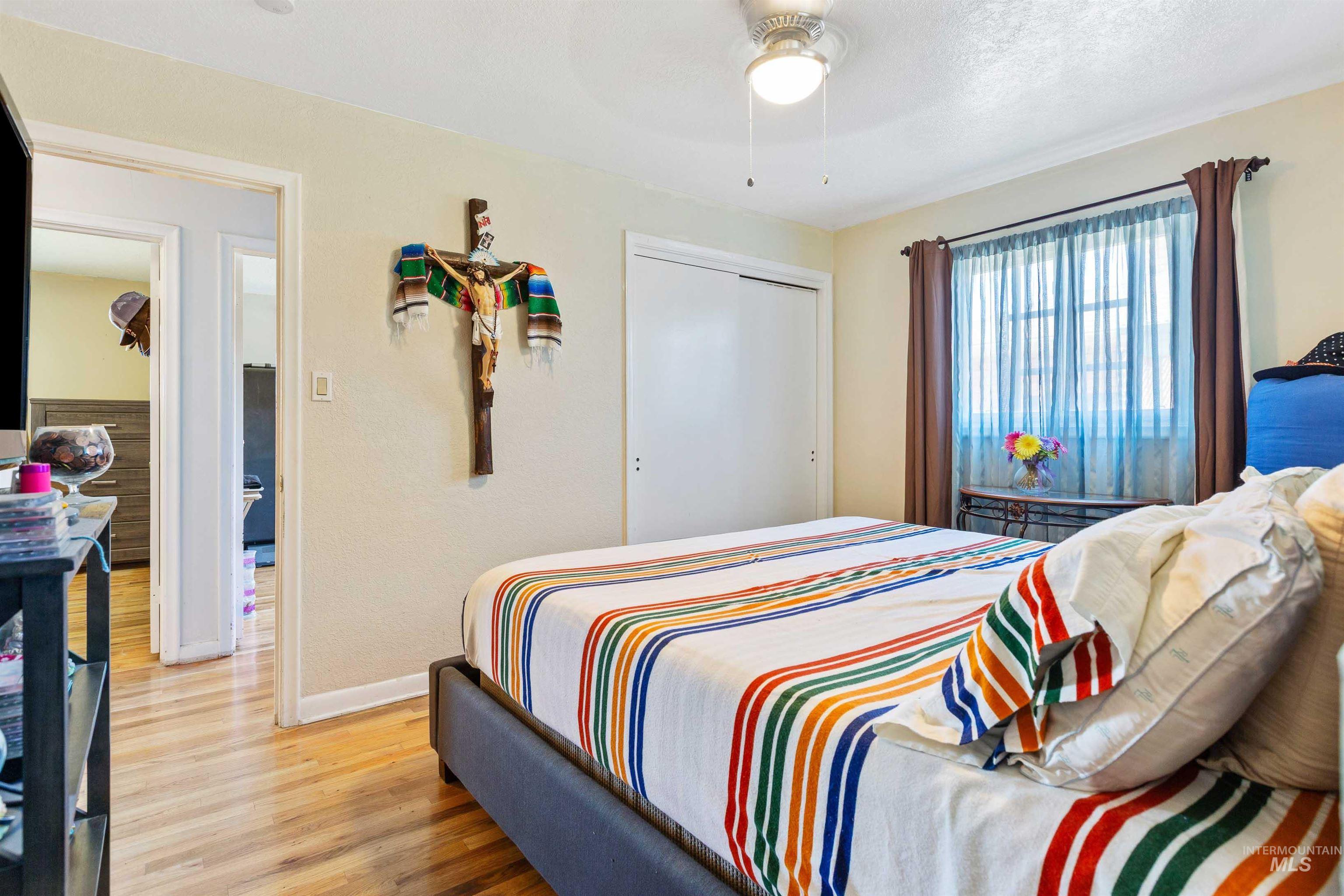Bedroom with light wood-style flooring, a ceiling fan, and a closet