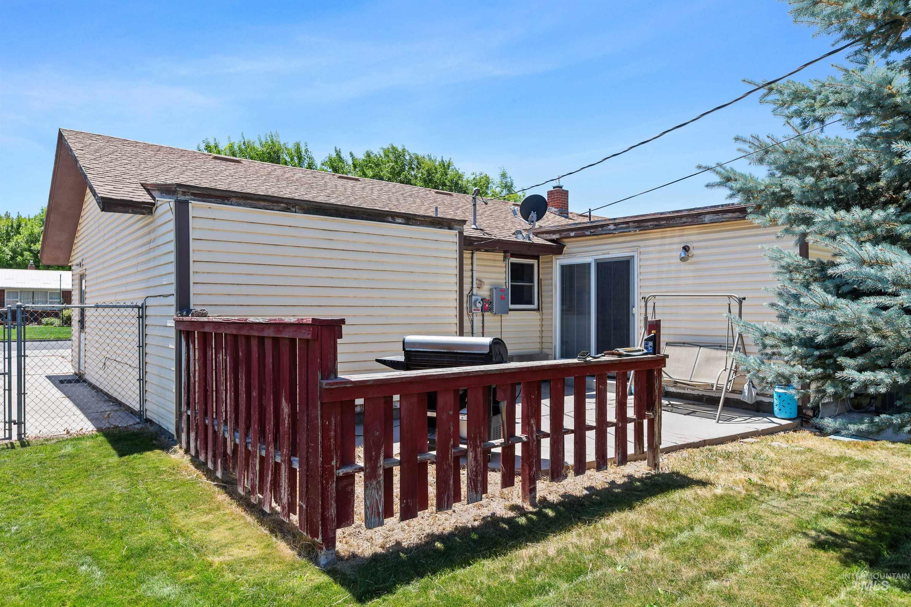 Back of house featuring a chimney, a gate, and a shingled roof