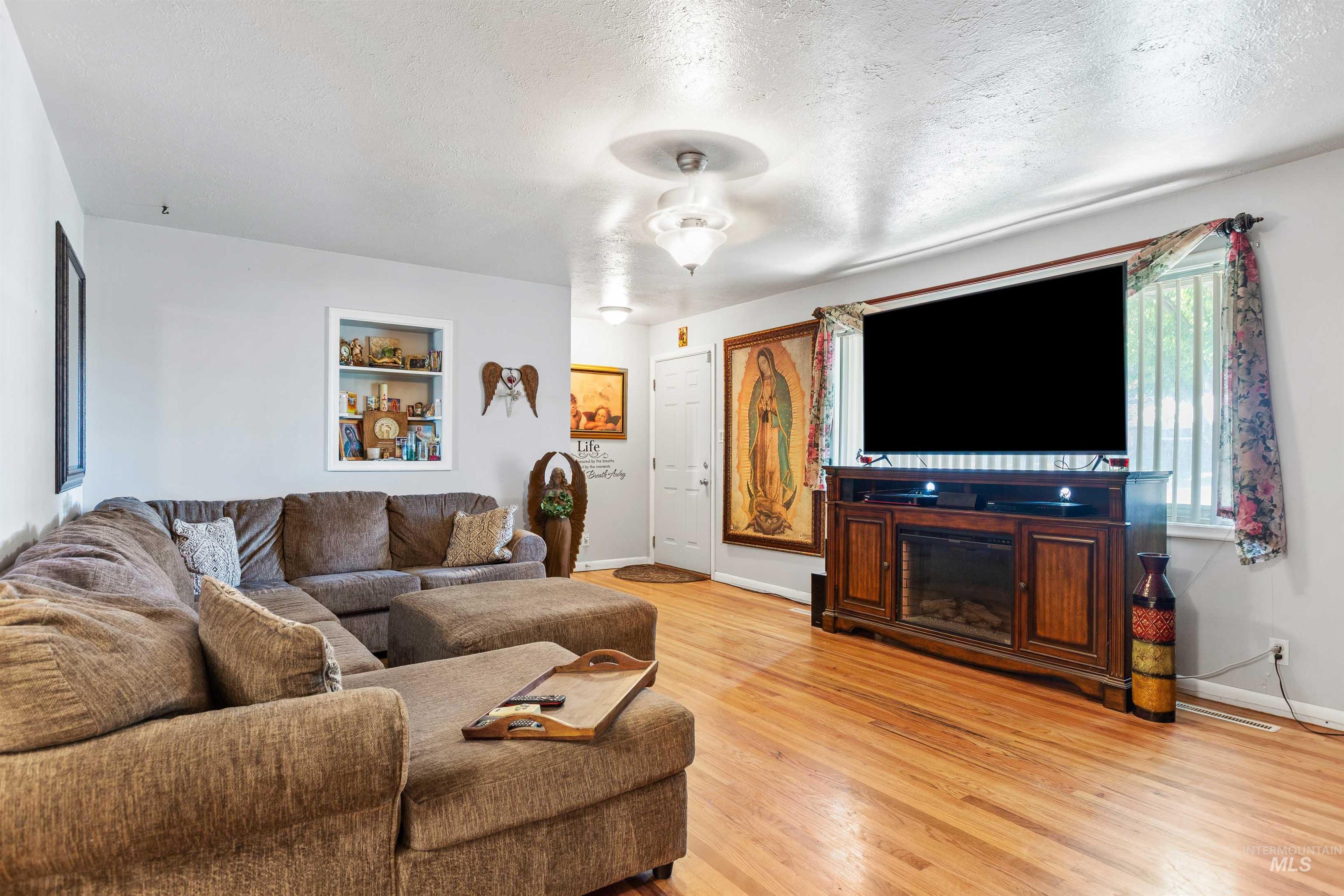Living room with light wood-type flooring and a textured ceiling