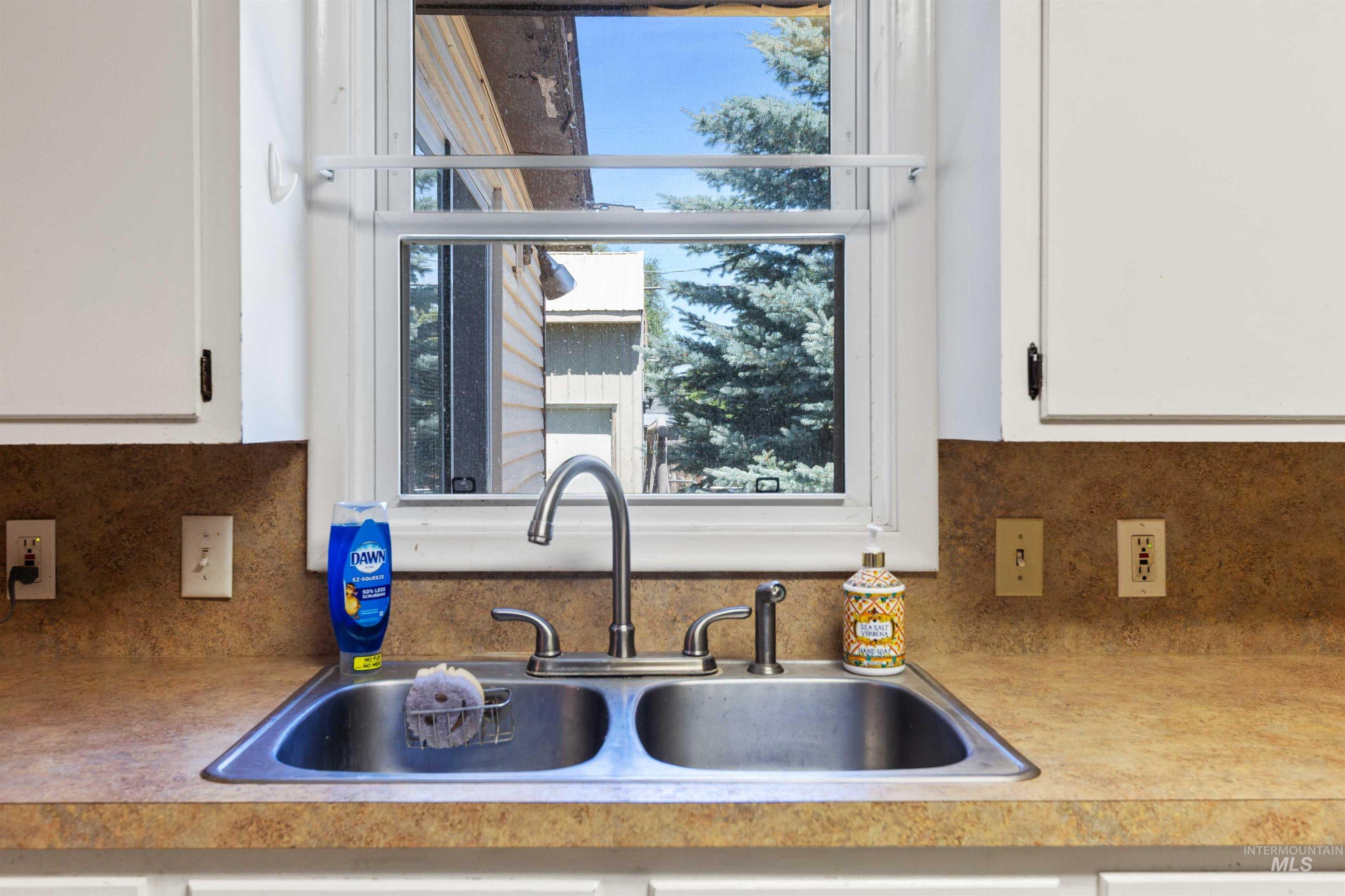 Kitchen with white cabinetry, light countertops, and decorative backsplash