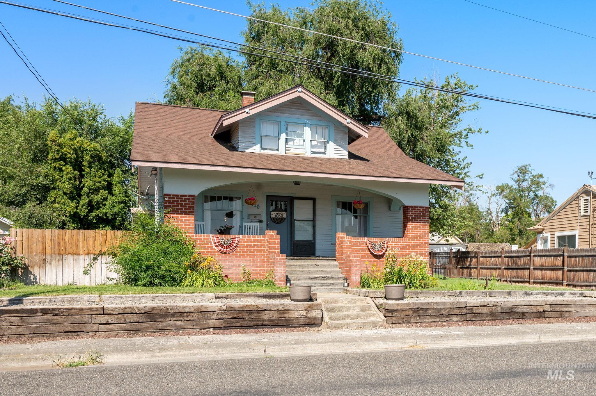 Bungalow with brick siding, covered porch, a chimney, and a shingled roof