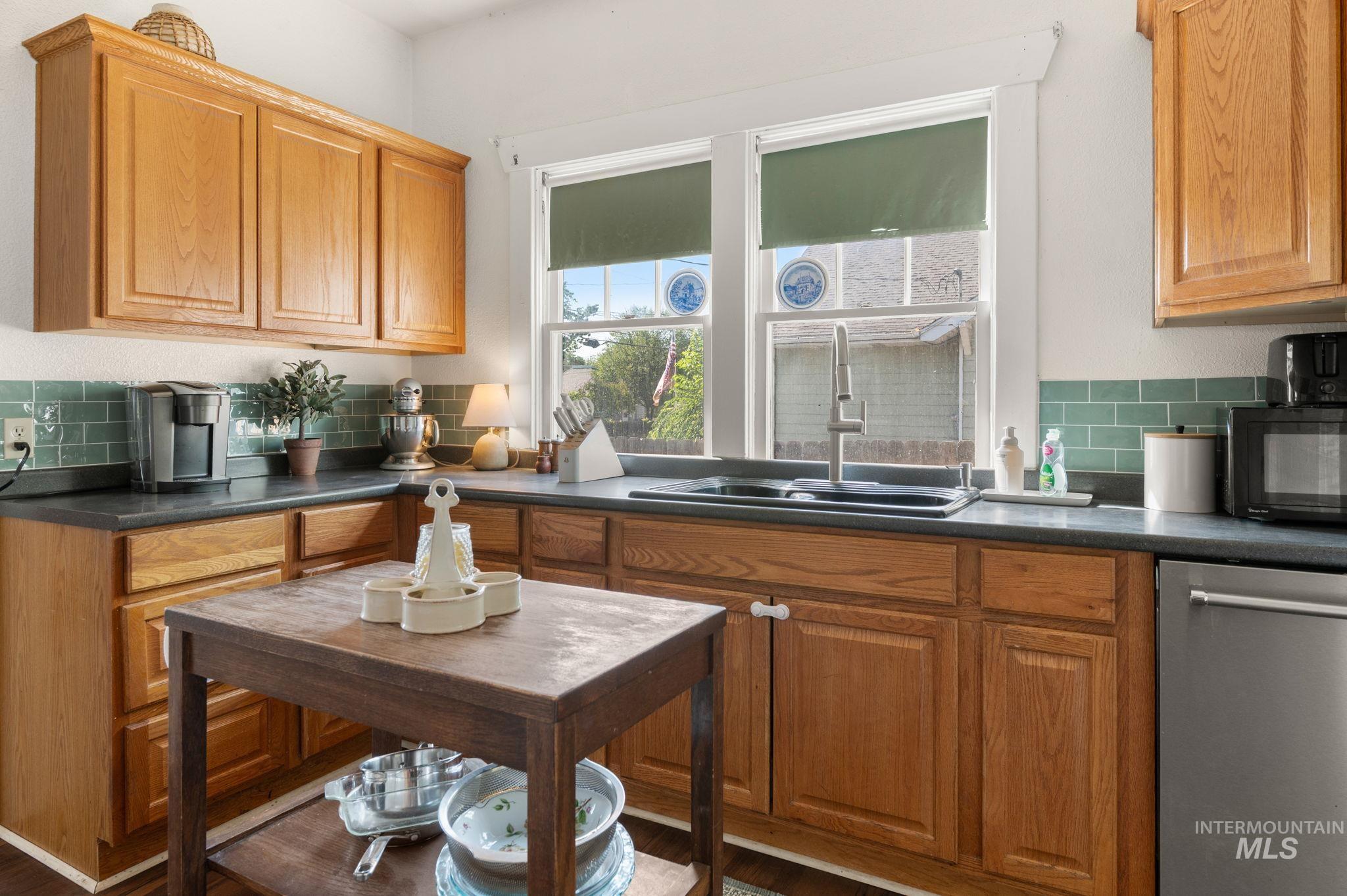 Kitchen with dishwasher, black microwave, tasteful backsplash, and dark countertops