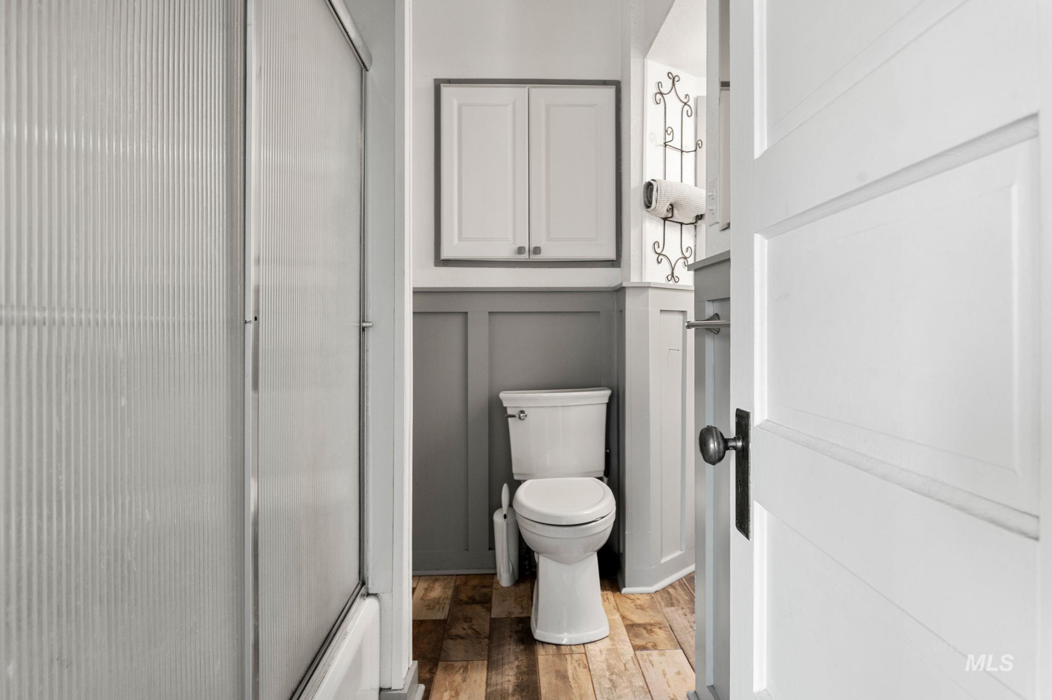 Bathroom featuring a decorative wall, wood finished floors, and wainscoting