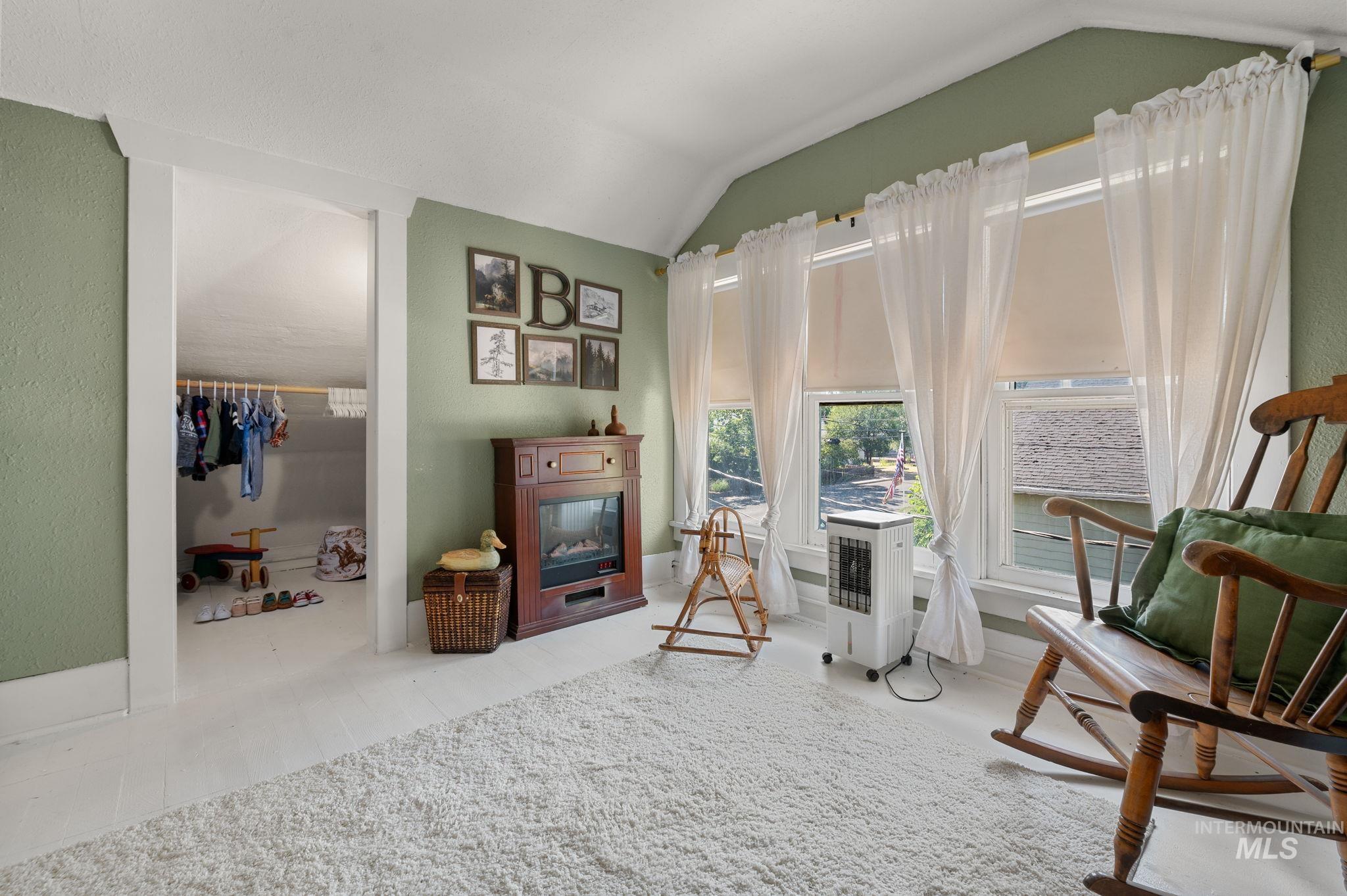 Sitting room featuring vaulted ceiling and a glass covered fireplace