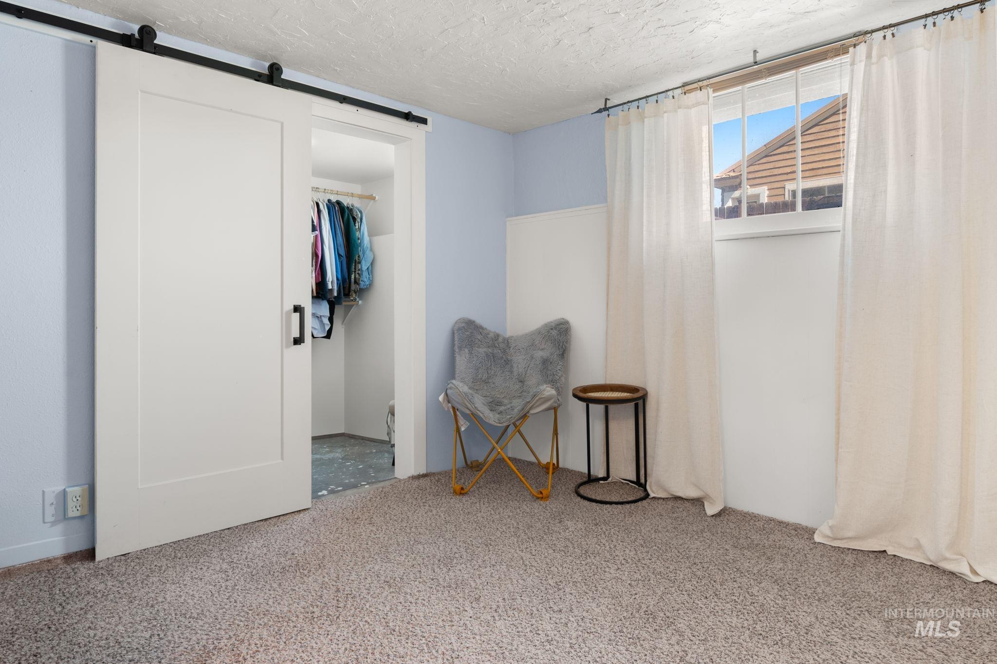 Living area with carpet, a barn door, and a textured ceiling