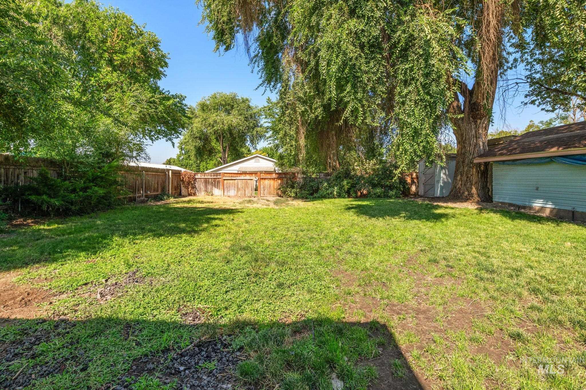Fenced backyard featuring a storage unit